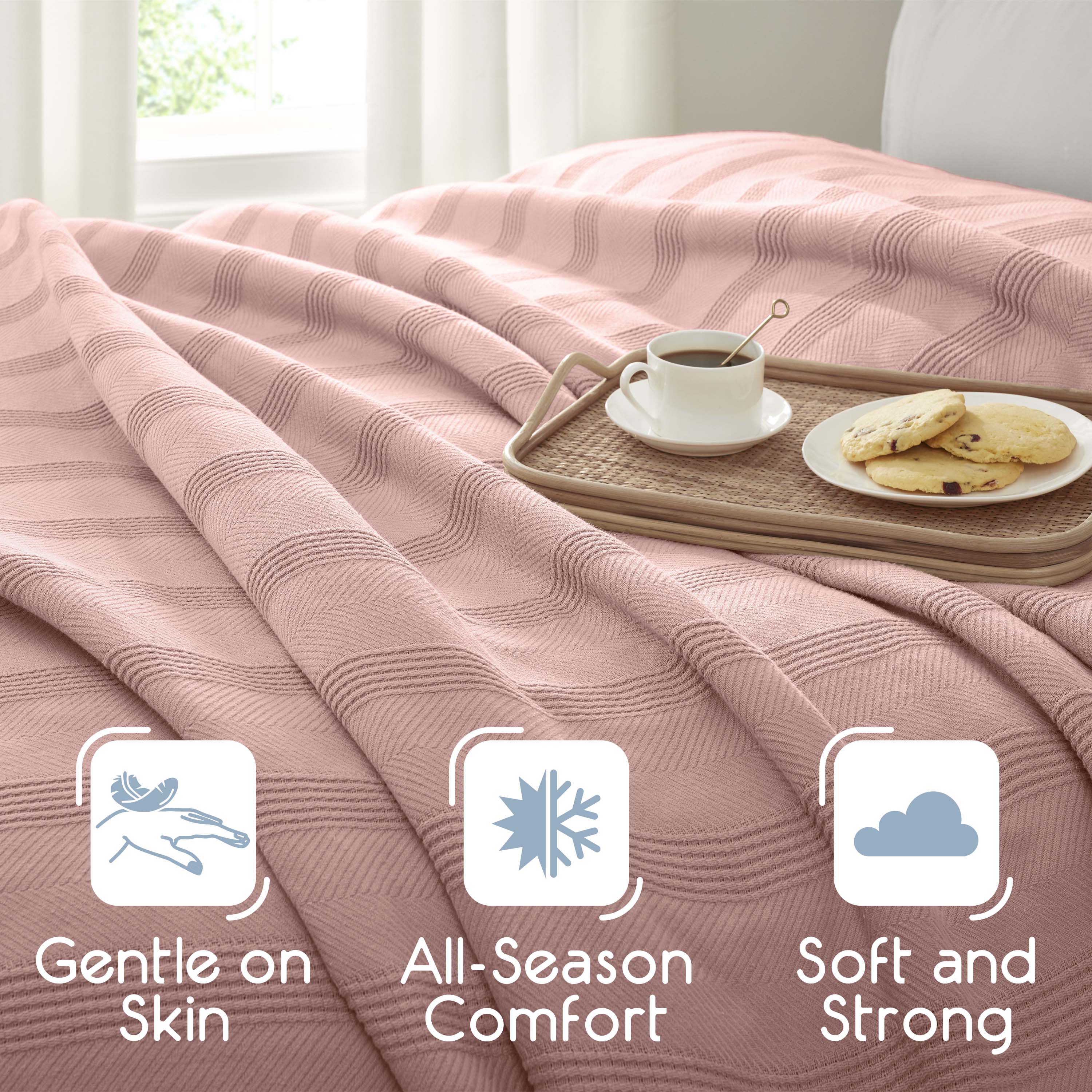 Light pink cotton blanket draped over a bed with a tray holding a cup of coffee and cookies.