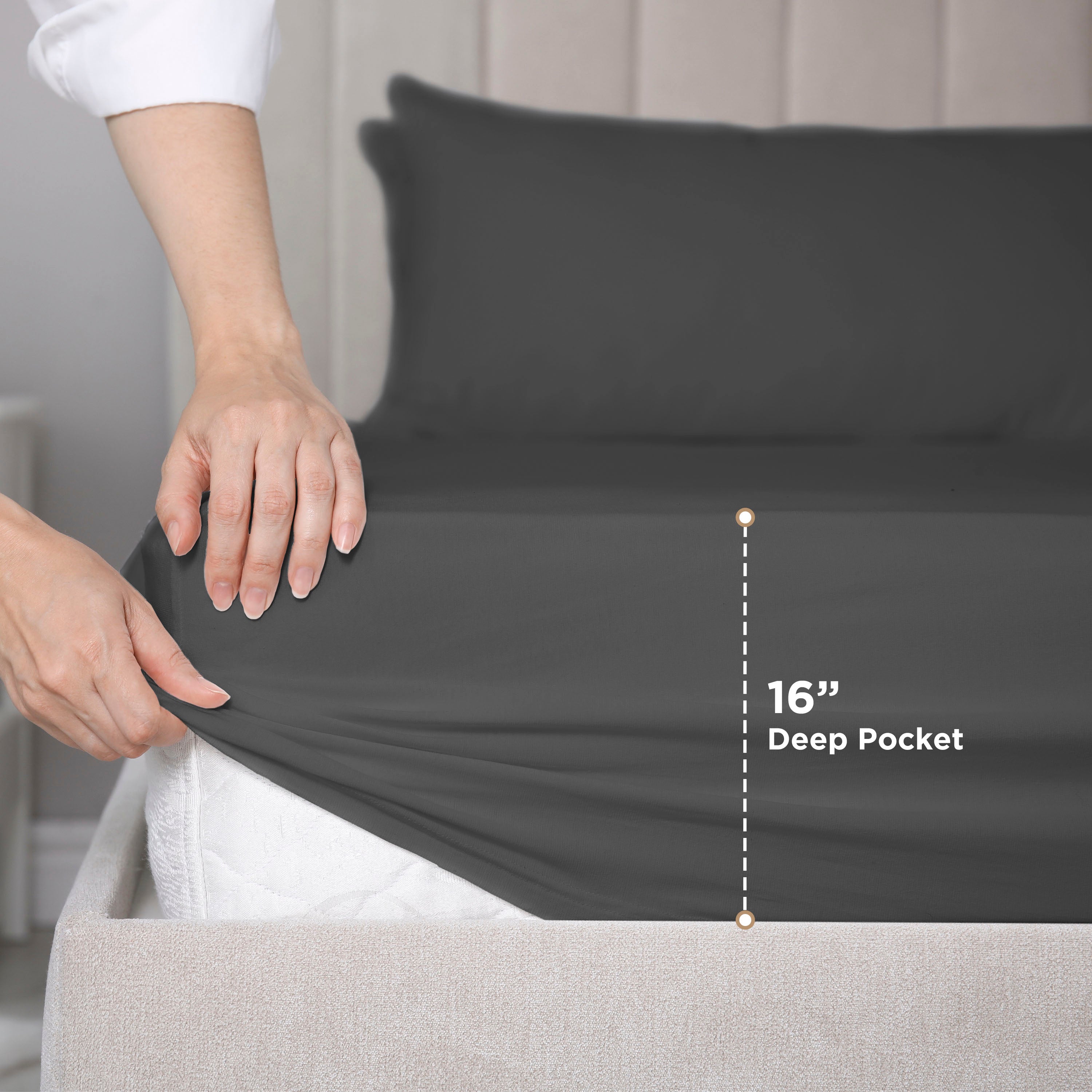 Hands adjusting a dark gray fitted sheet on a mattress, showing a 16-inch deep pocket feature.