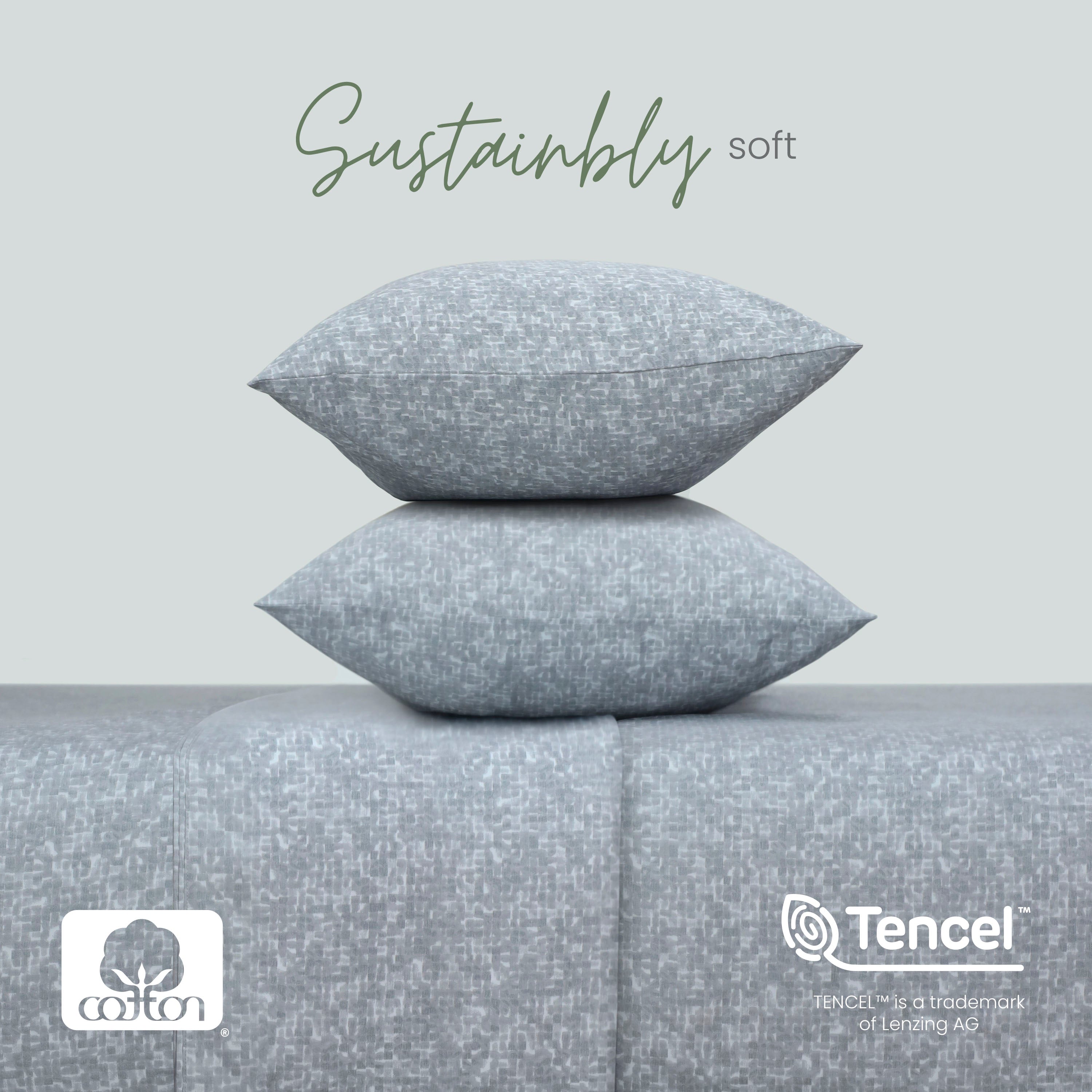 Two charcoal textured pillows stacked on a matching fabric surface with 'Sustainably soft' text and Tencel logo.