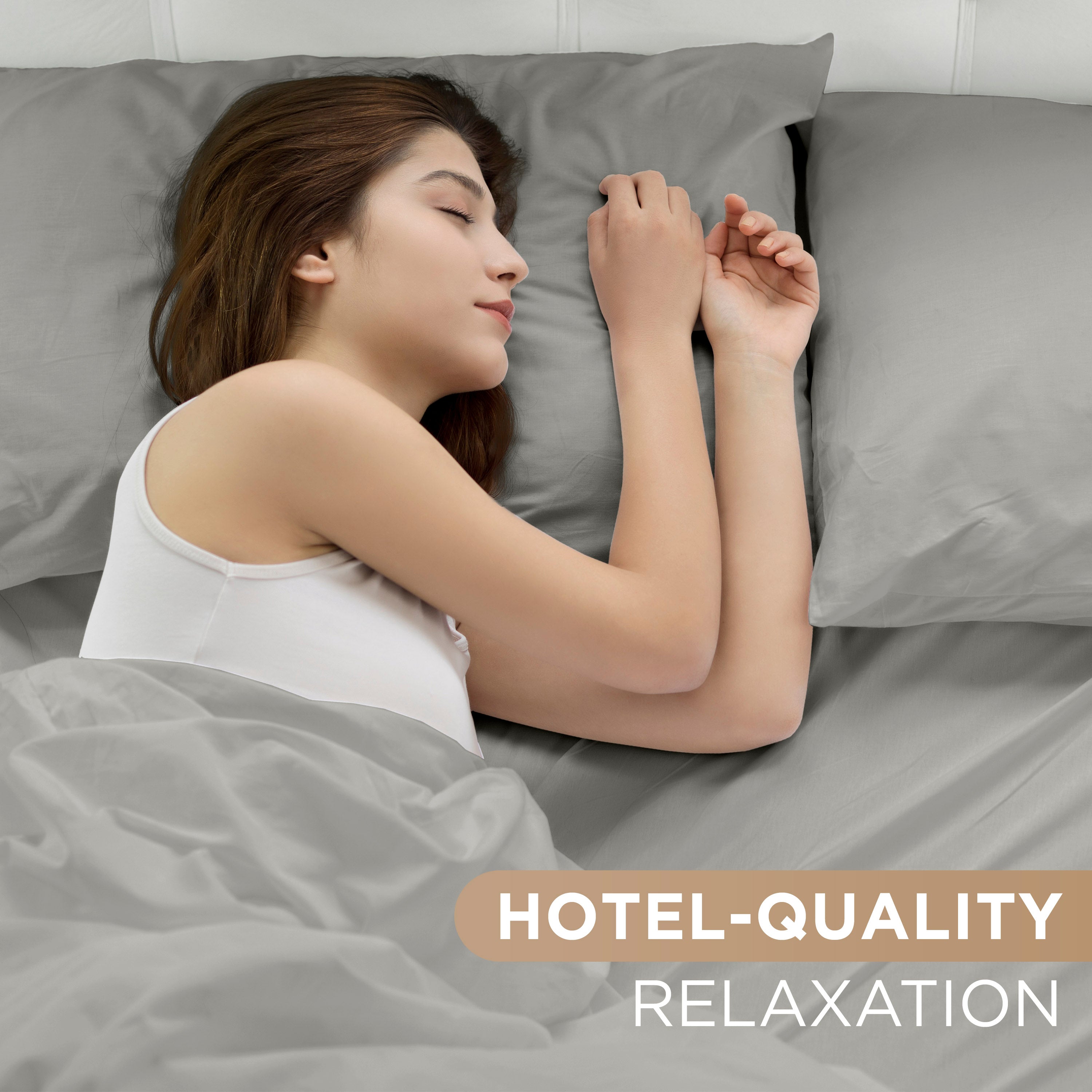 A person sleeps peacefully on gray sheets with matching pillows in a cozy bedroom setting.