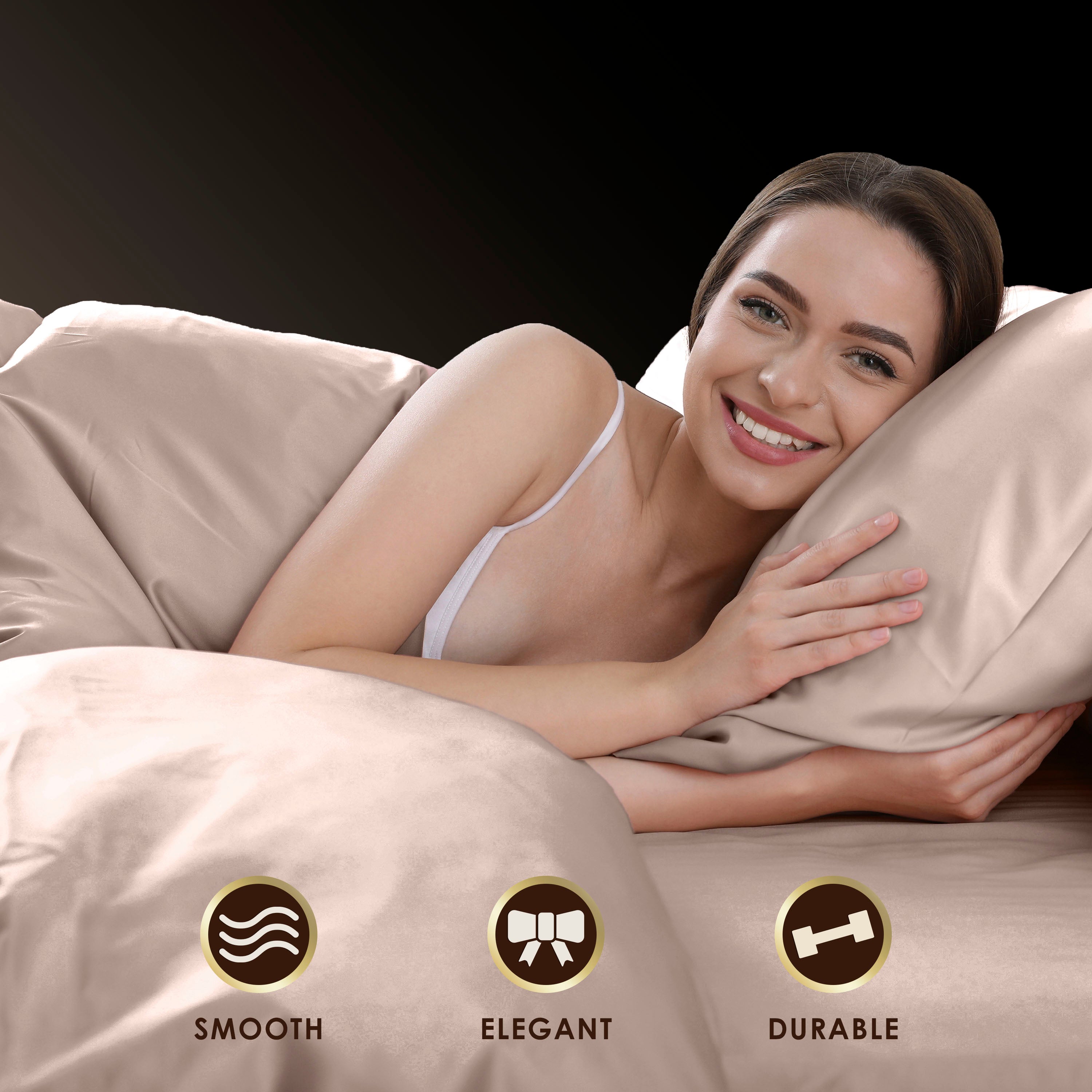 A woman smiles while lying on satin sheets and pillows, showcasing a smooth and elegant bedding set.