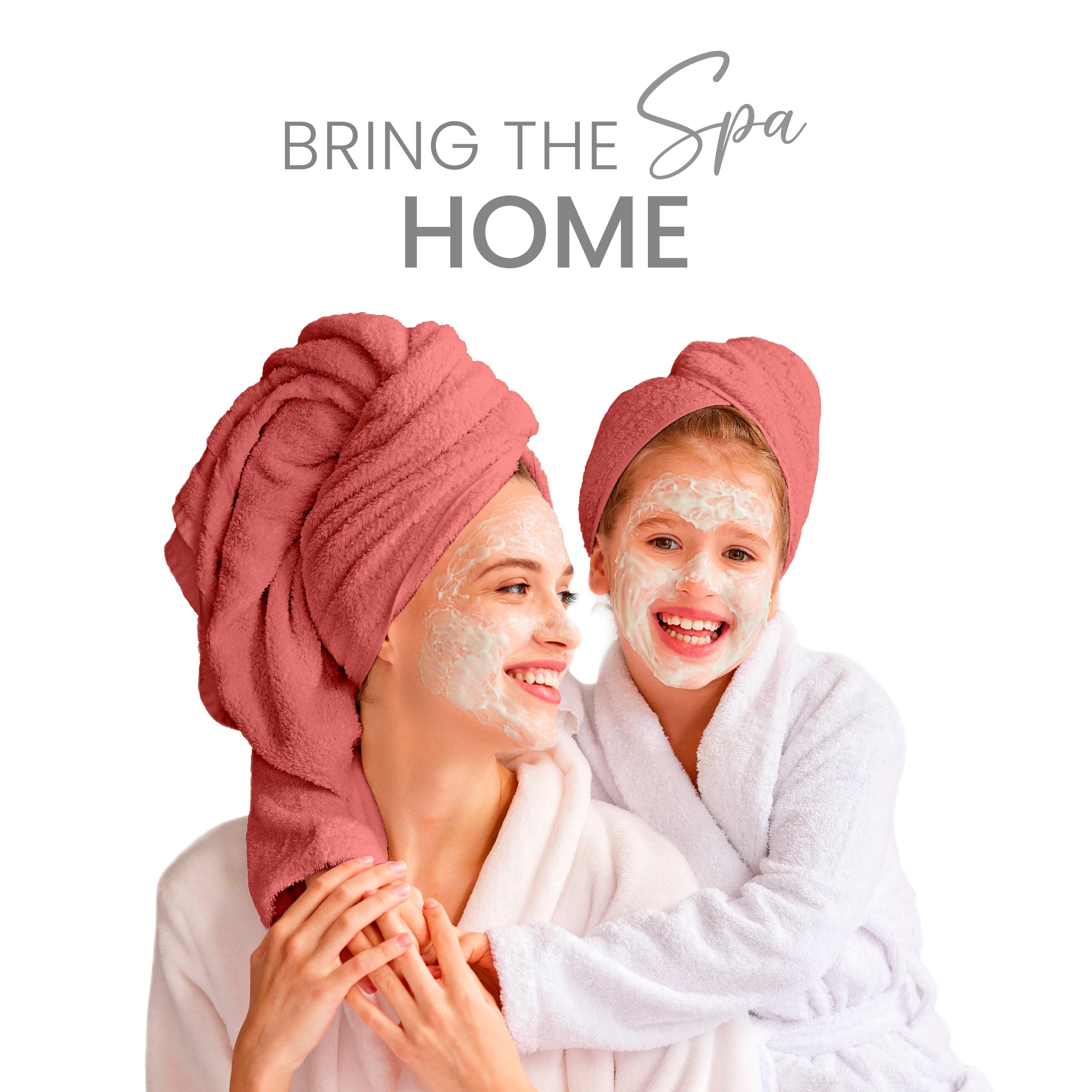 Two people with facial masks and towels on their heads, wearing bathrobes, smiling together.