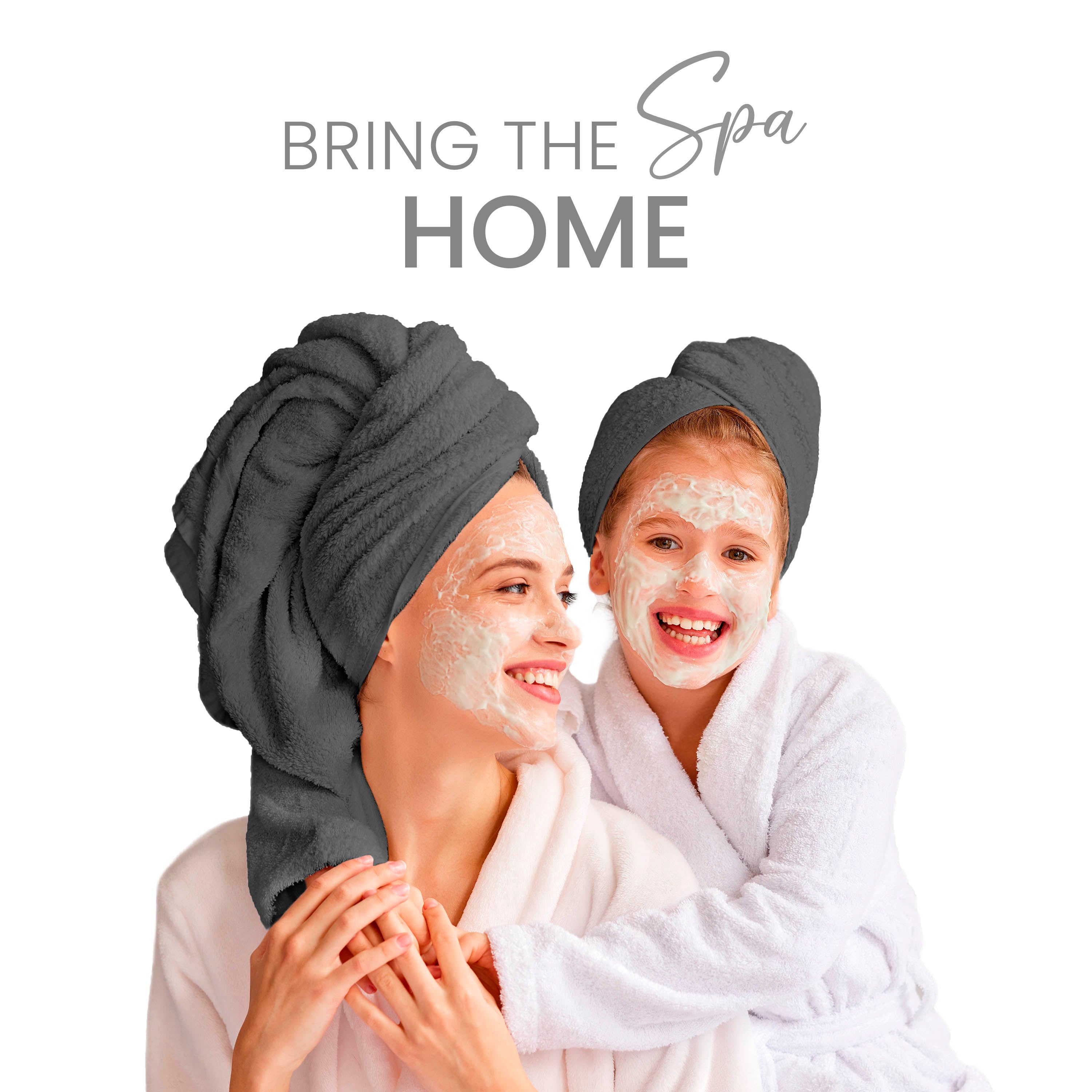 Two women wearing towels on their heads and bathrobes, smiling with facial masks on their faces.