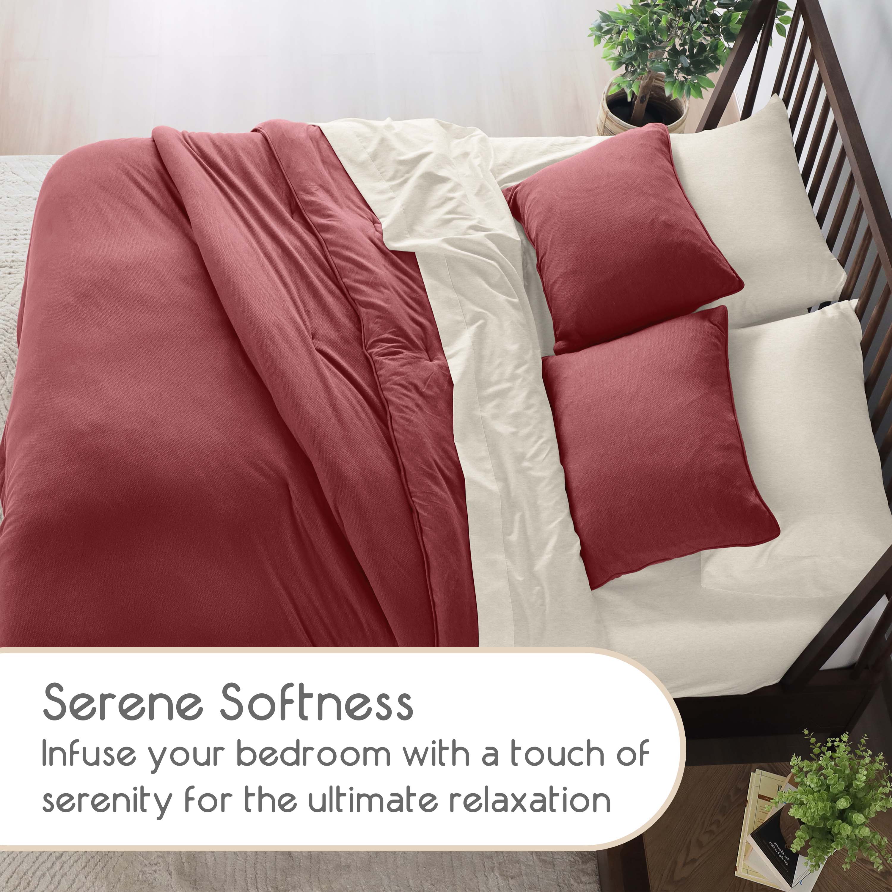 Comforter set featuring a burgundy comforter and cream-colored sheets with two matching pillows on a bed.