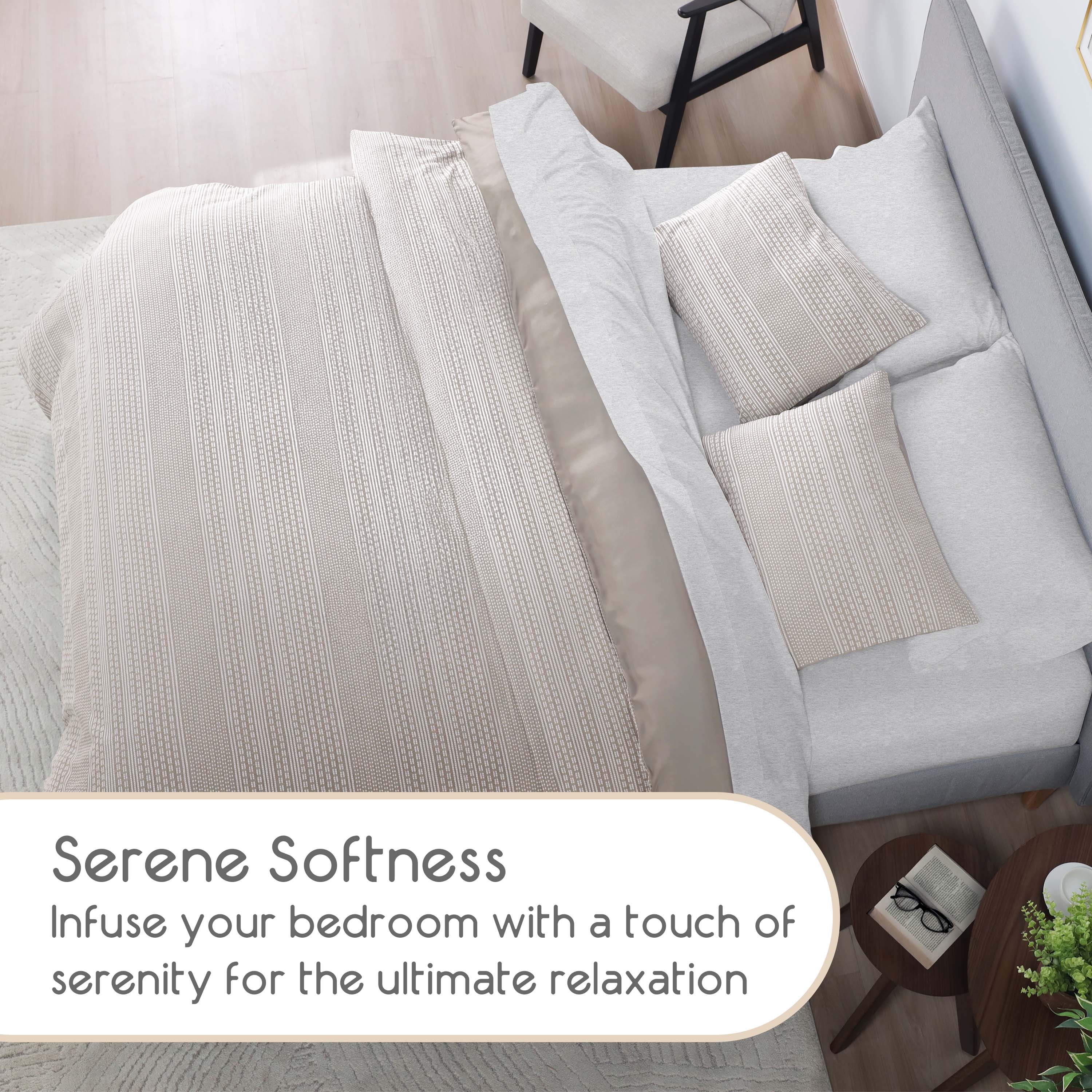 Comforter set featuring a textured beige design with matching pillows on a bed, alongside a small table with decor.