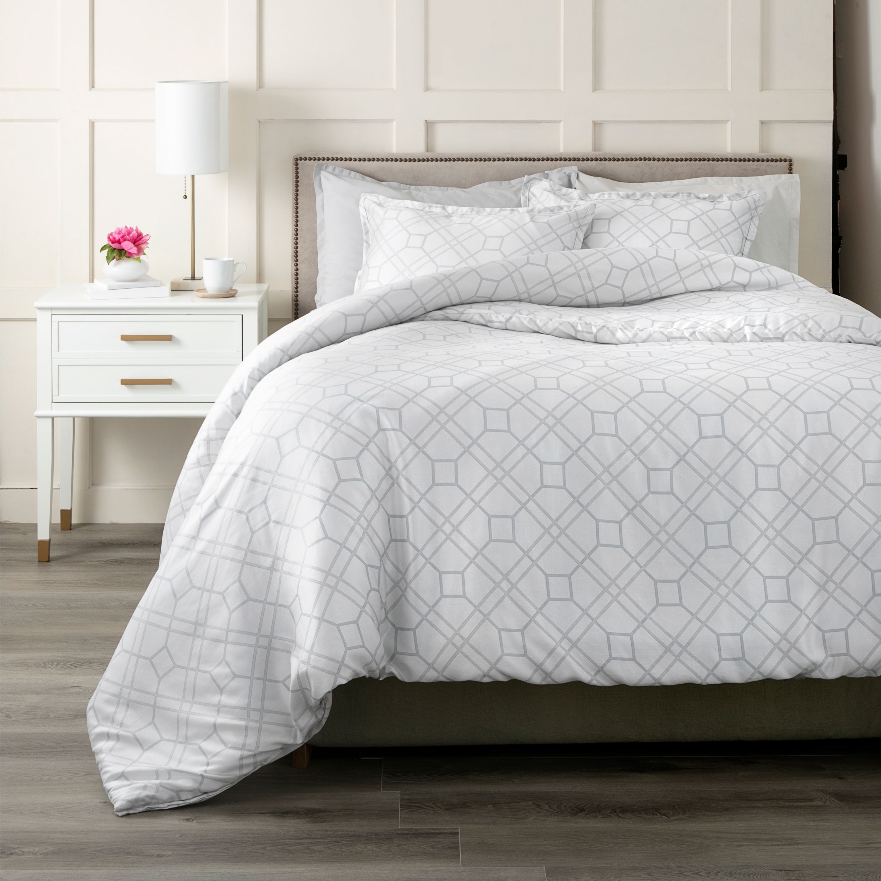 Light gray comforter set with a geometric trellis pattern, paired with matching pillow shams on a bed.