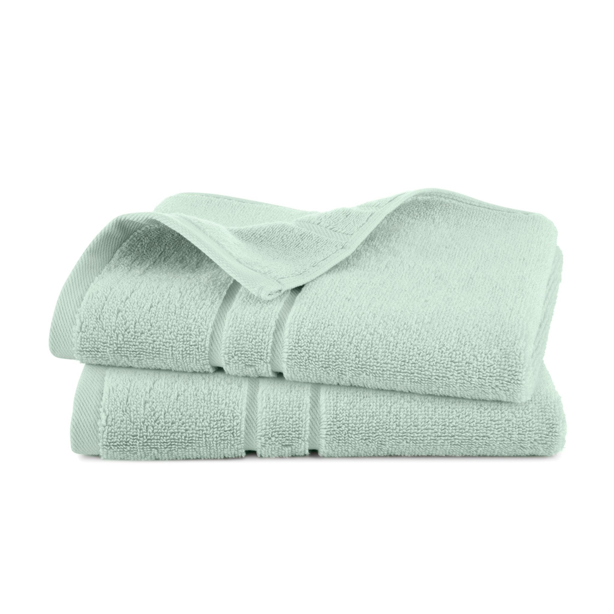 Two light green hand towels stacked on a white background