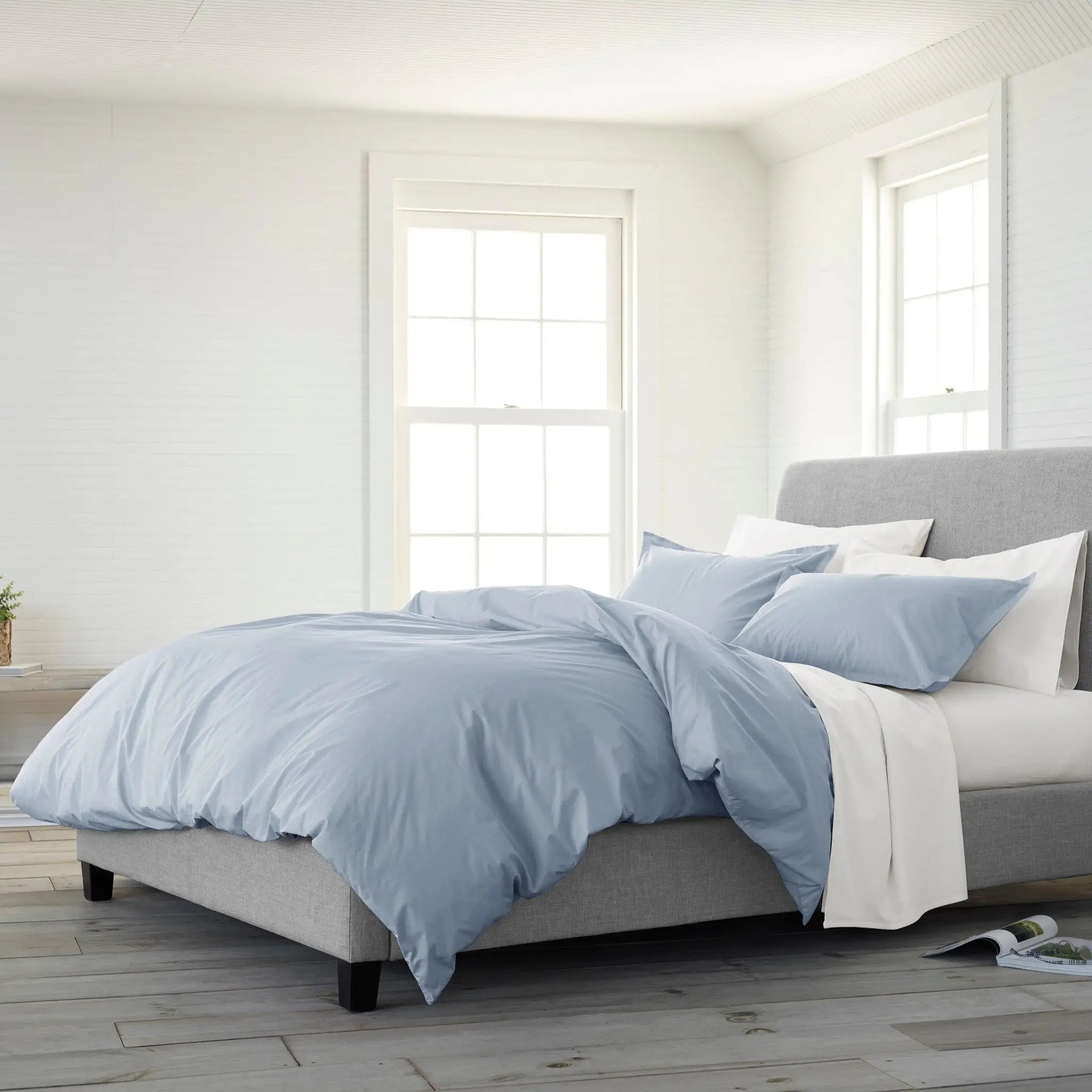 Bed with light blue comforter set in a bright bedroom