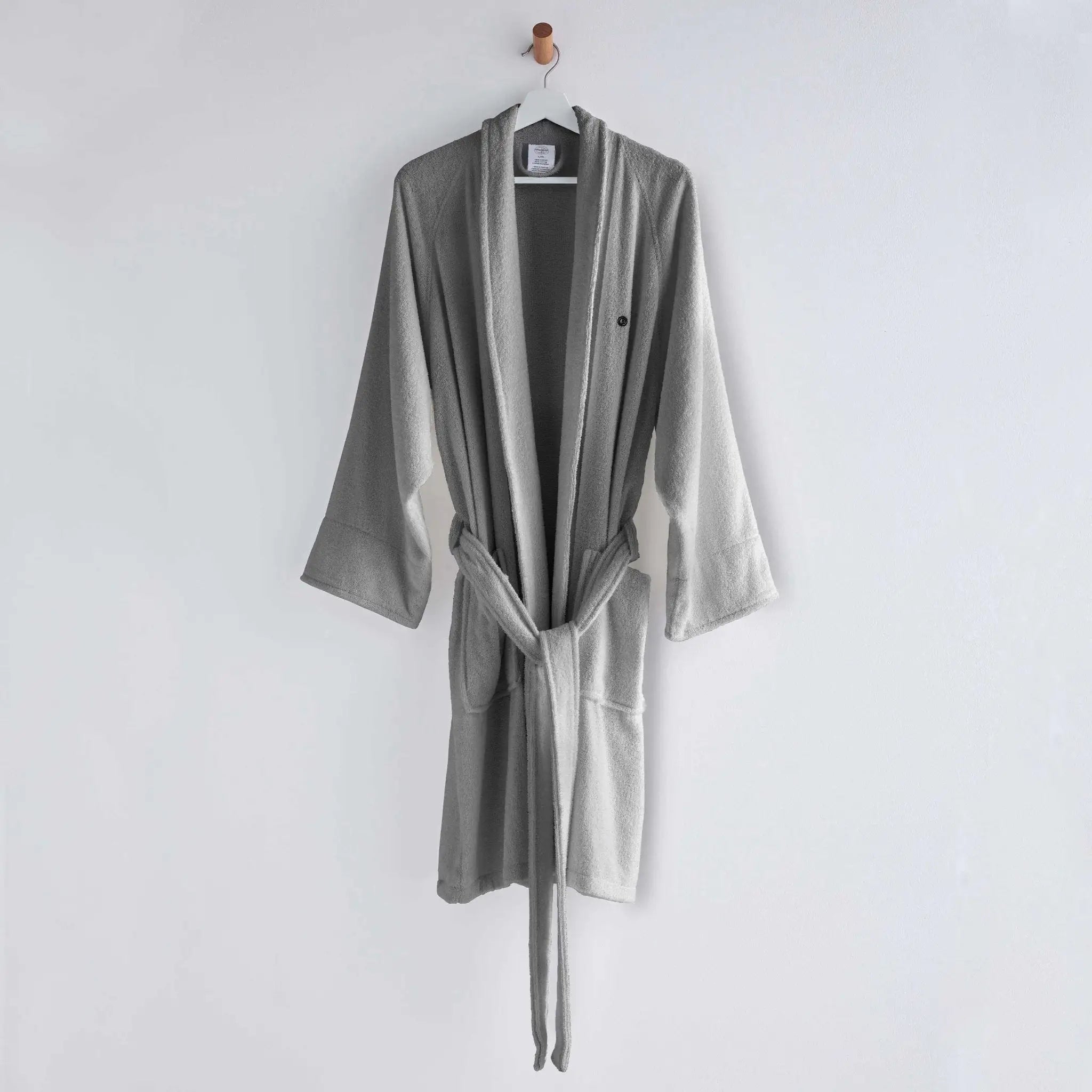 A light gray bathrobe with a matching tie belt, hanging on a wooden hanger against a plain white wall.