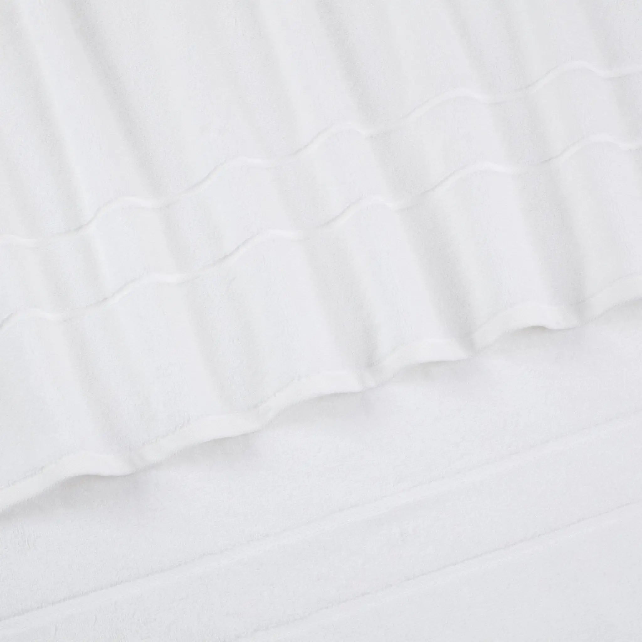 Close-up of a white textured fabric with a wavy stitched pattern and soft folds.
