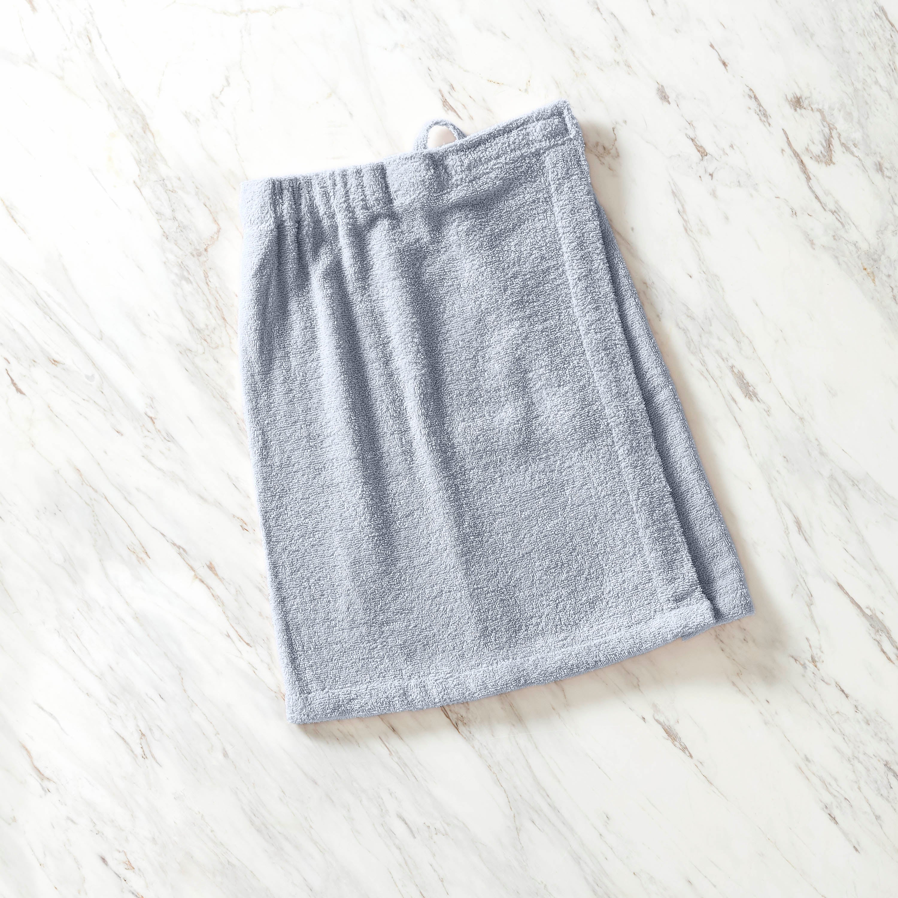 Light blue youth shower wrap made of soft, absorbent fabric, laid flat on a marble surface.