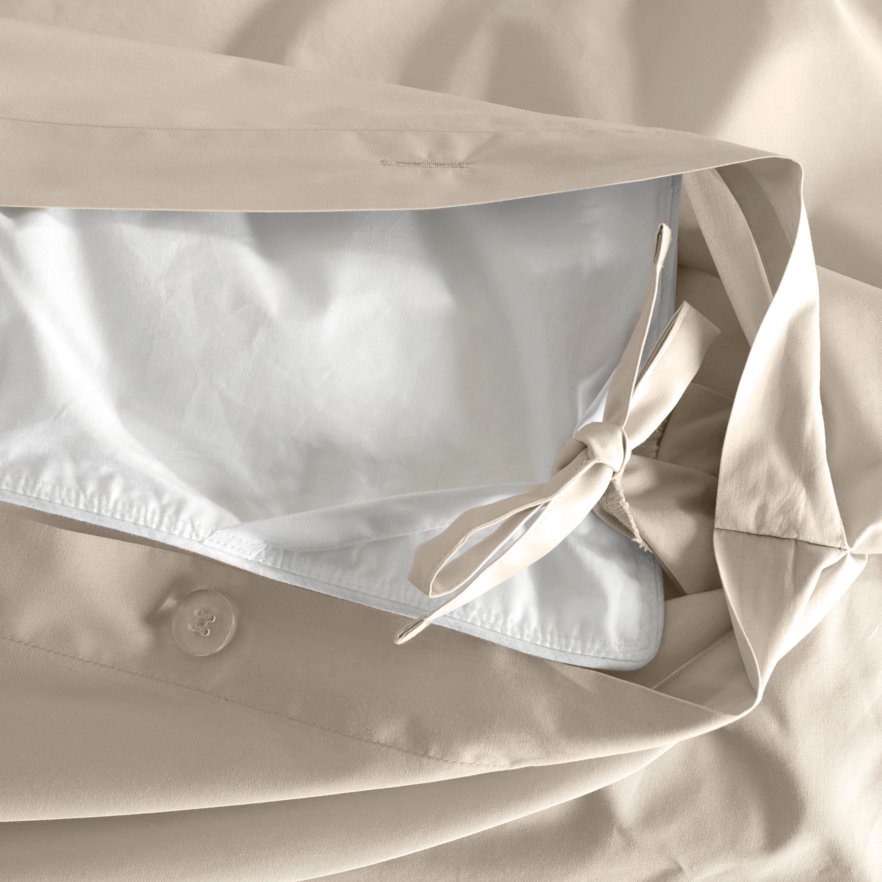 Duvet cover with a beige exterior and white interior, featuring a button closure and ties for securing the duvet.