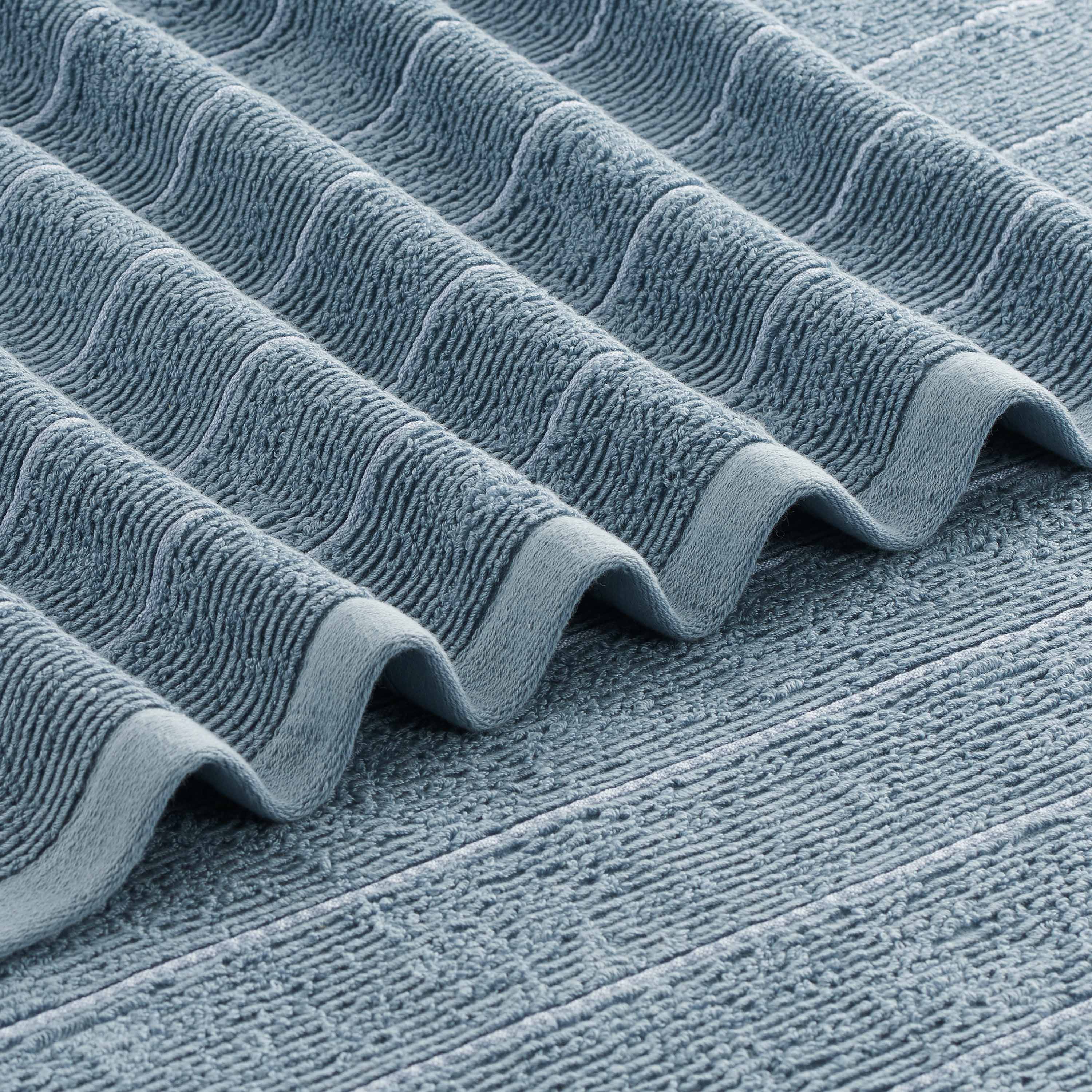 Textured blue towel with slub stripe pattern, folded in waves.