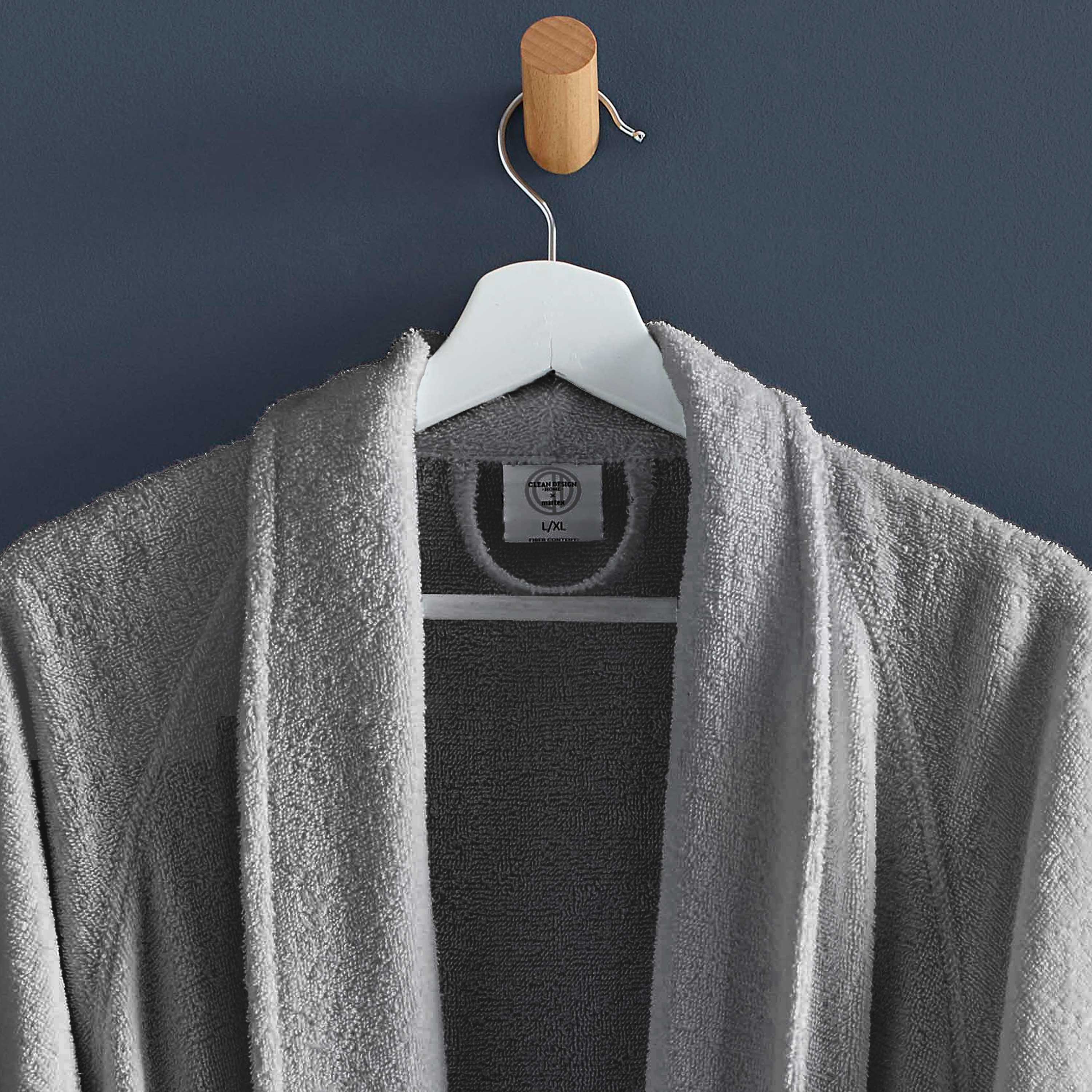 Gray terry bath robe hanging on a wooden hook against a dark blue wall.