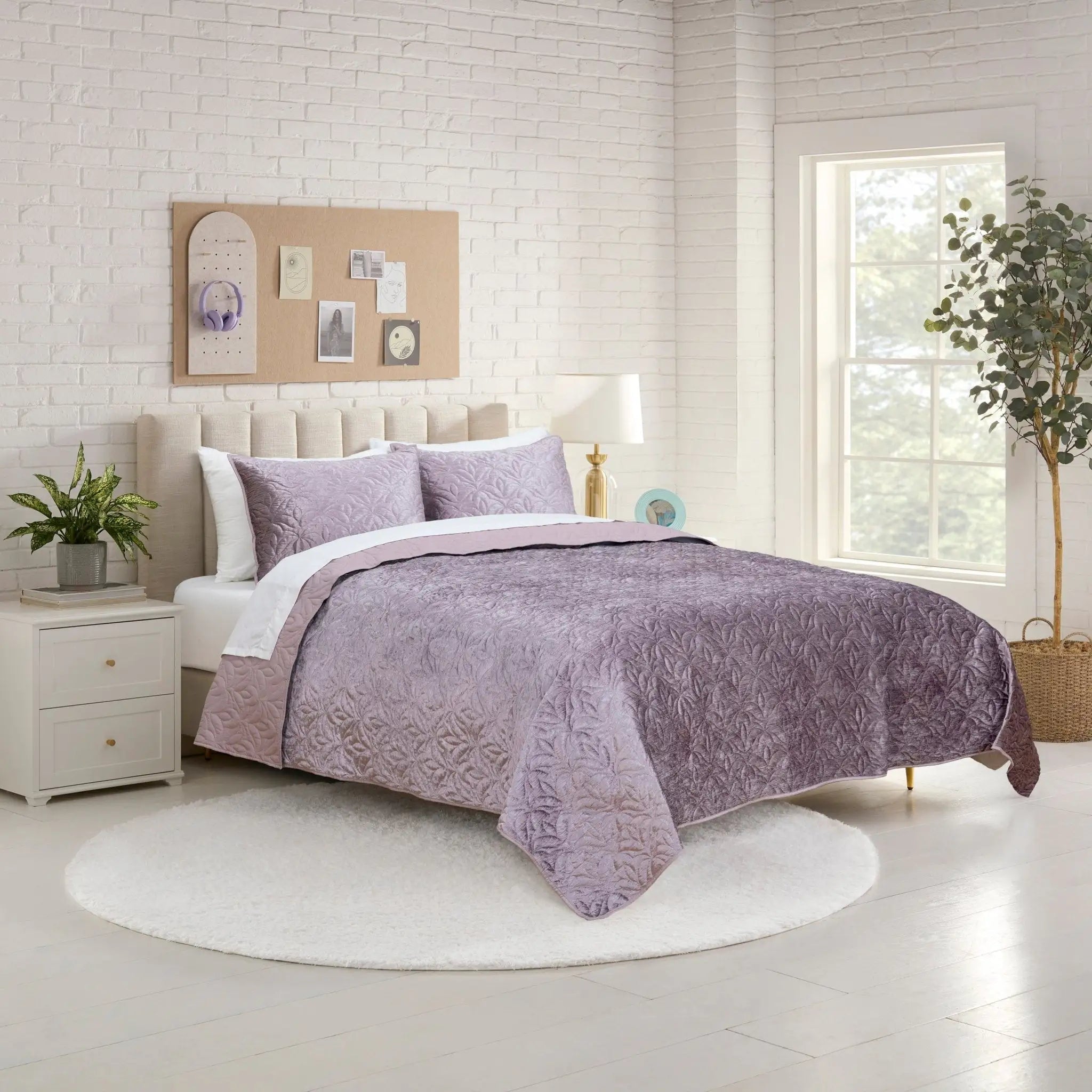 Bedroom with a bed covered in a purple quilt and pillow shams.