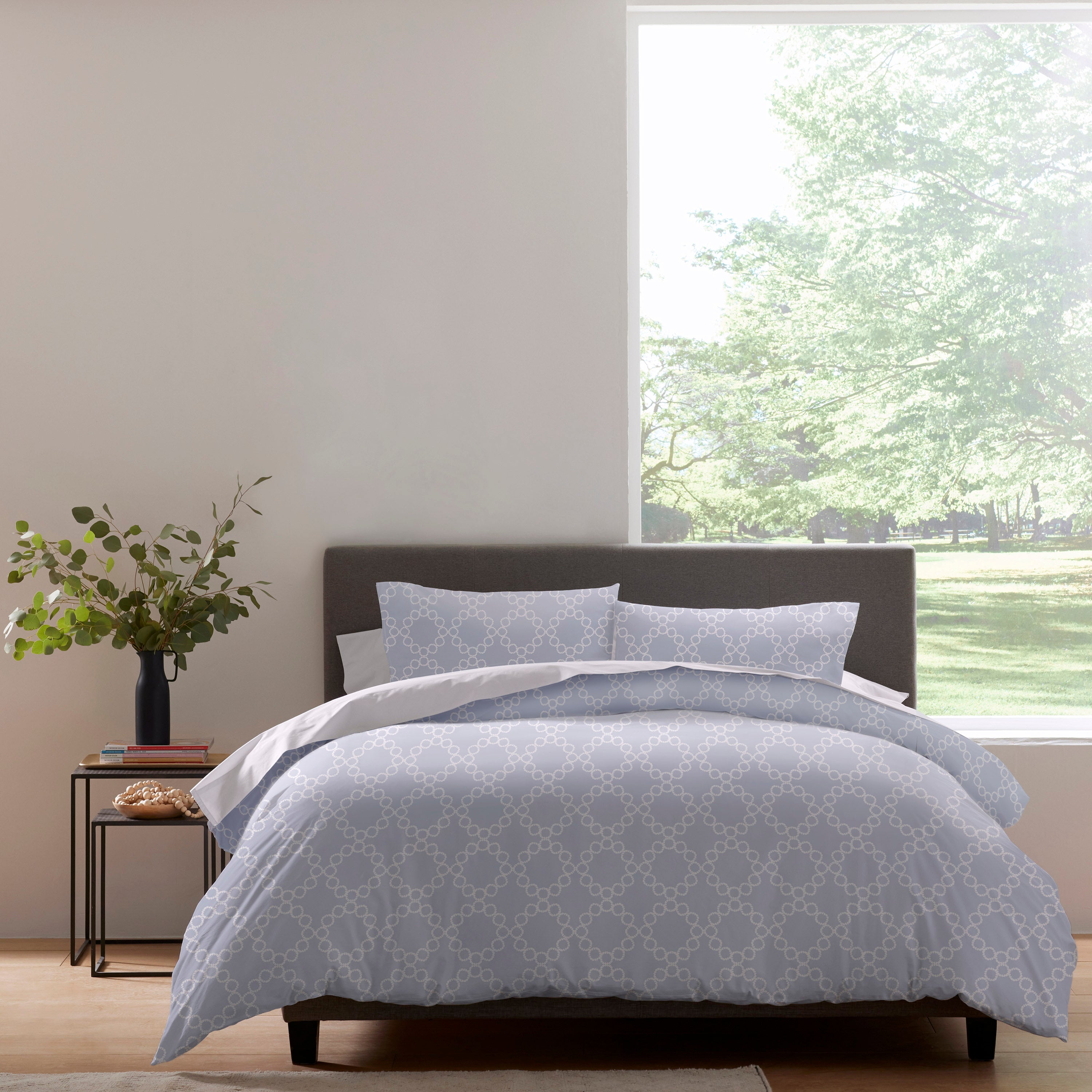 Duvet set featuring a light blue pattern with circular designs, arranged on a bed with matching pillows.