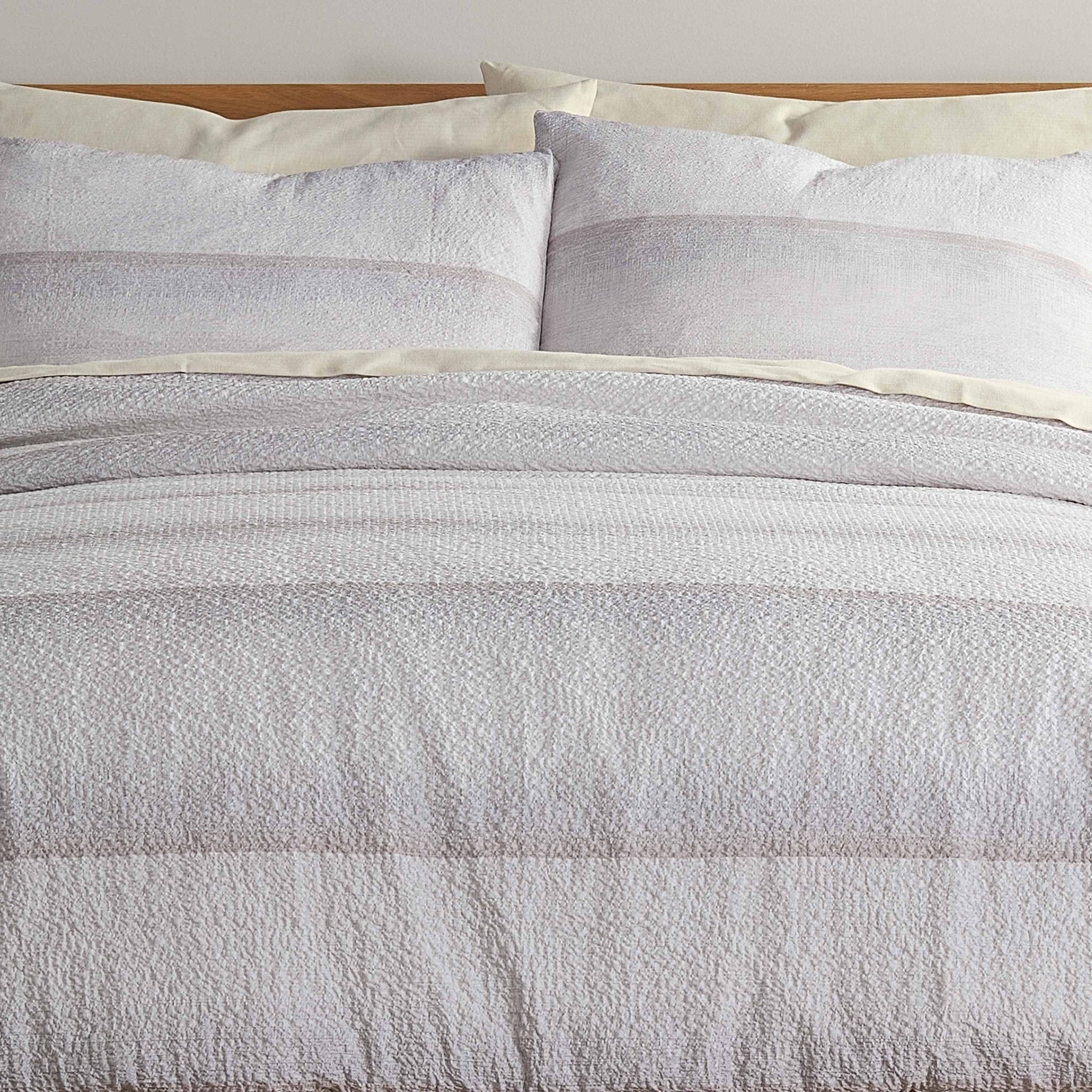Textured comforter set with striped pattern on a bed with white pillow shams.
