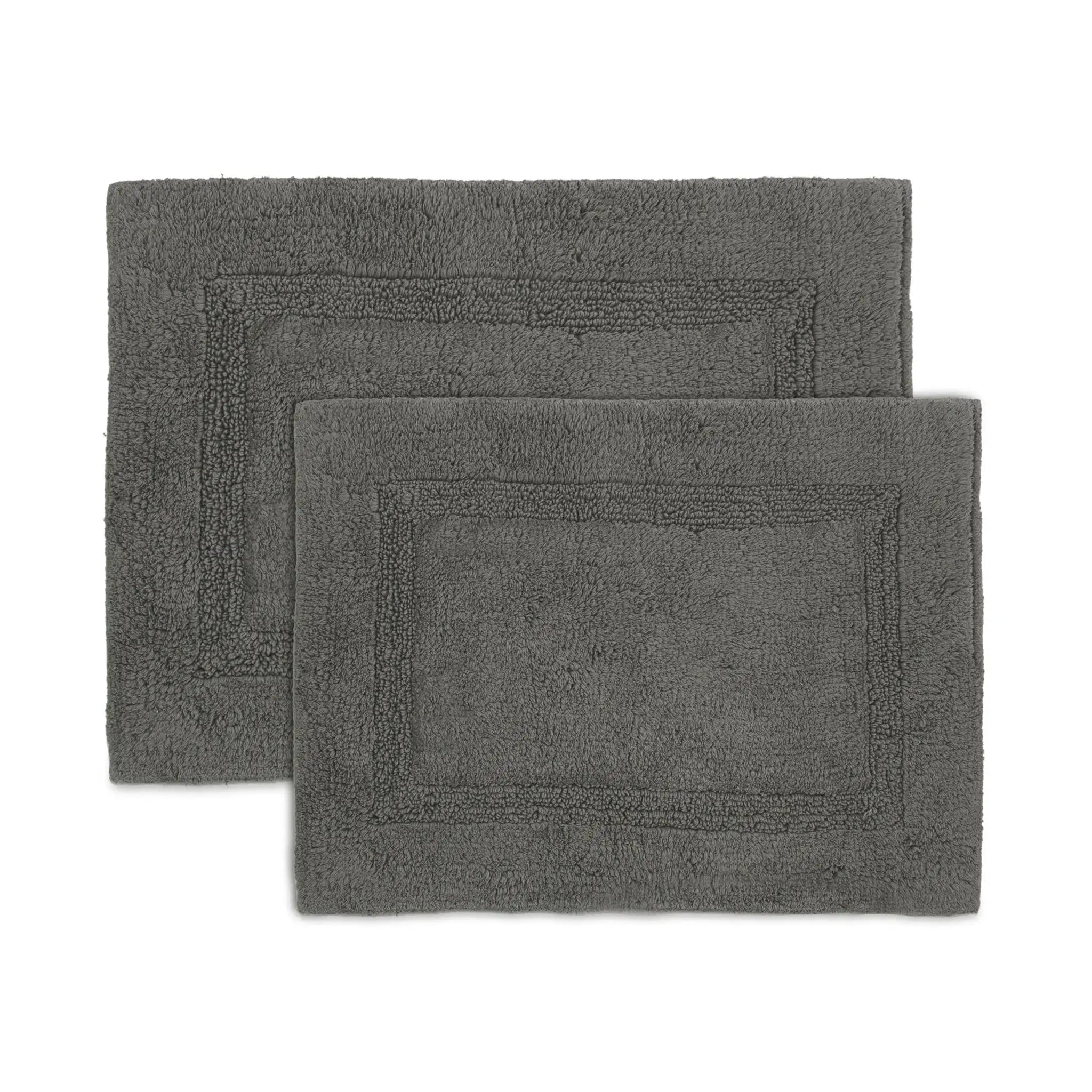 Two dark gray rectangular bath rugs with raised border detailing, shown overlapping on a plain white background.