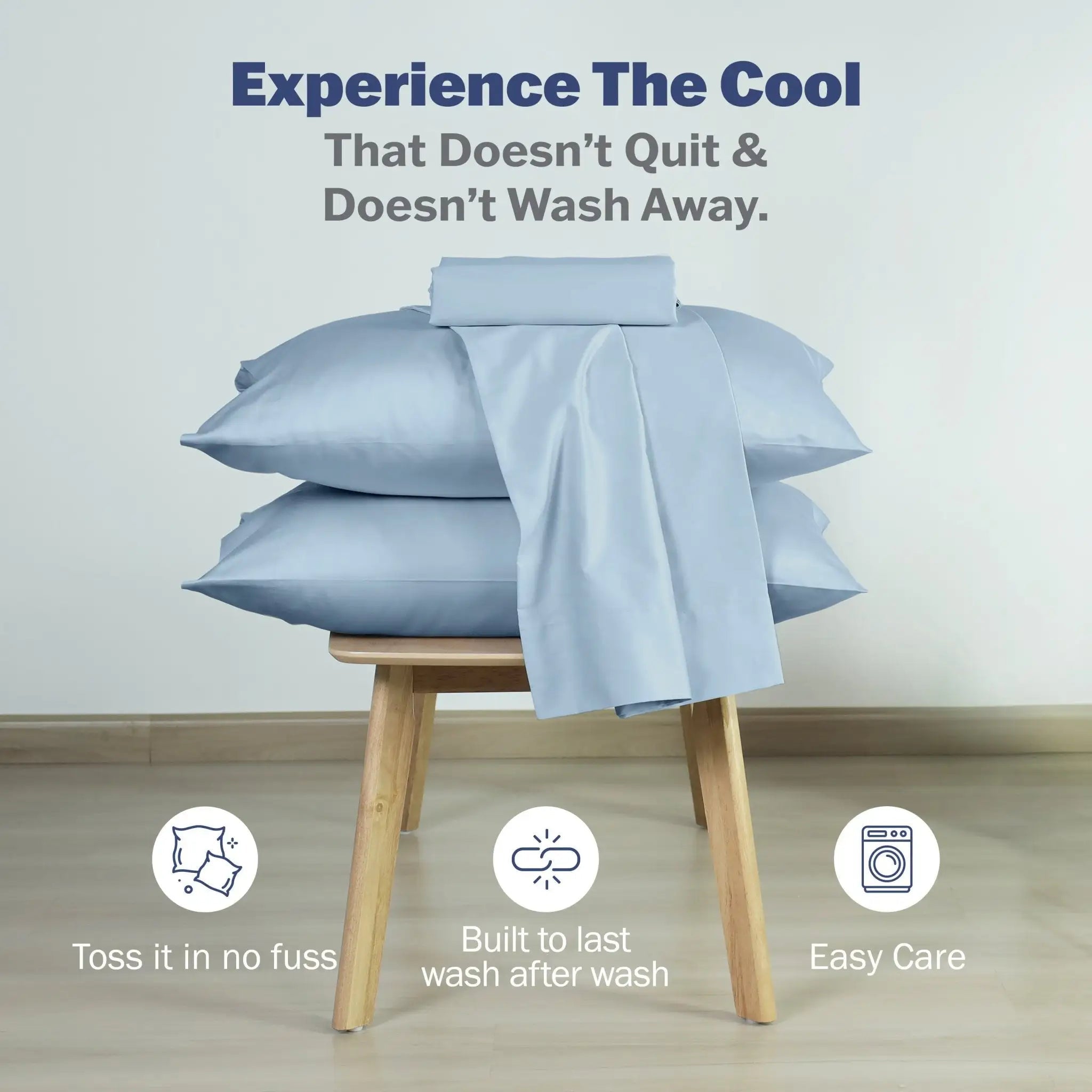 Light blue bedding, including pillows and a folded sheet, displayed on a wooden stool against a light gray wall. Promotional text at the top reads 'Experience The Cool That Doesn't Quit & Doesn't Wash Away.
