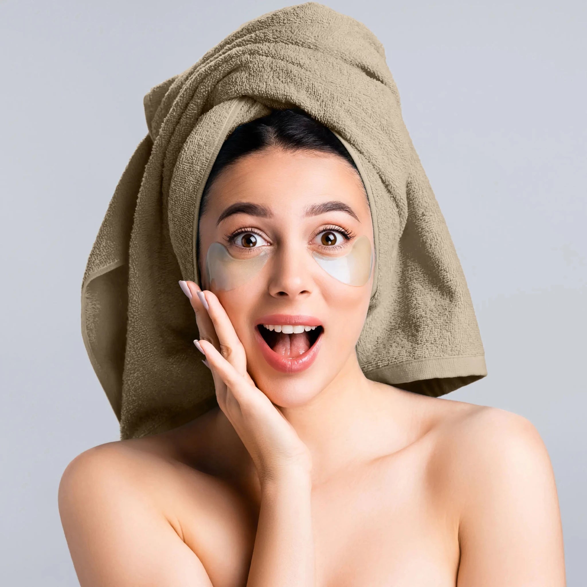 A woman with a beige towel wrapped around her head and eye patches under her eyes.