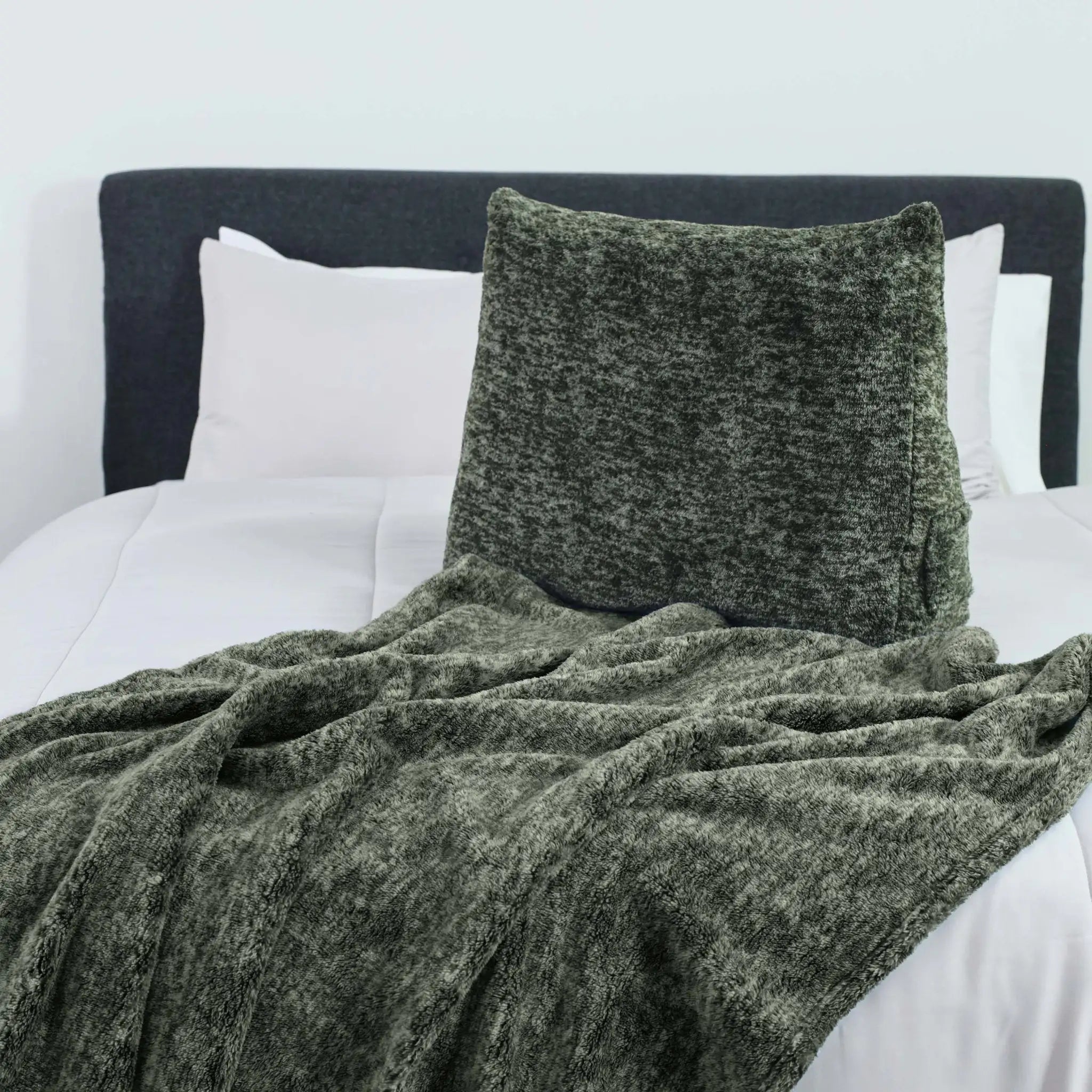 Green textured blanket and pillow on a bed with white pillows and headboard.