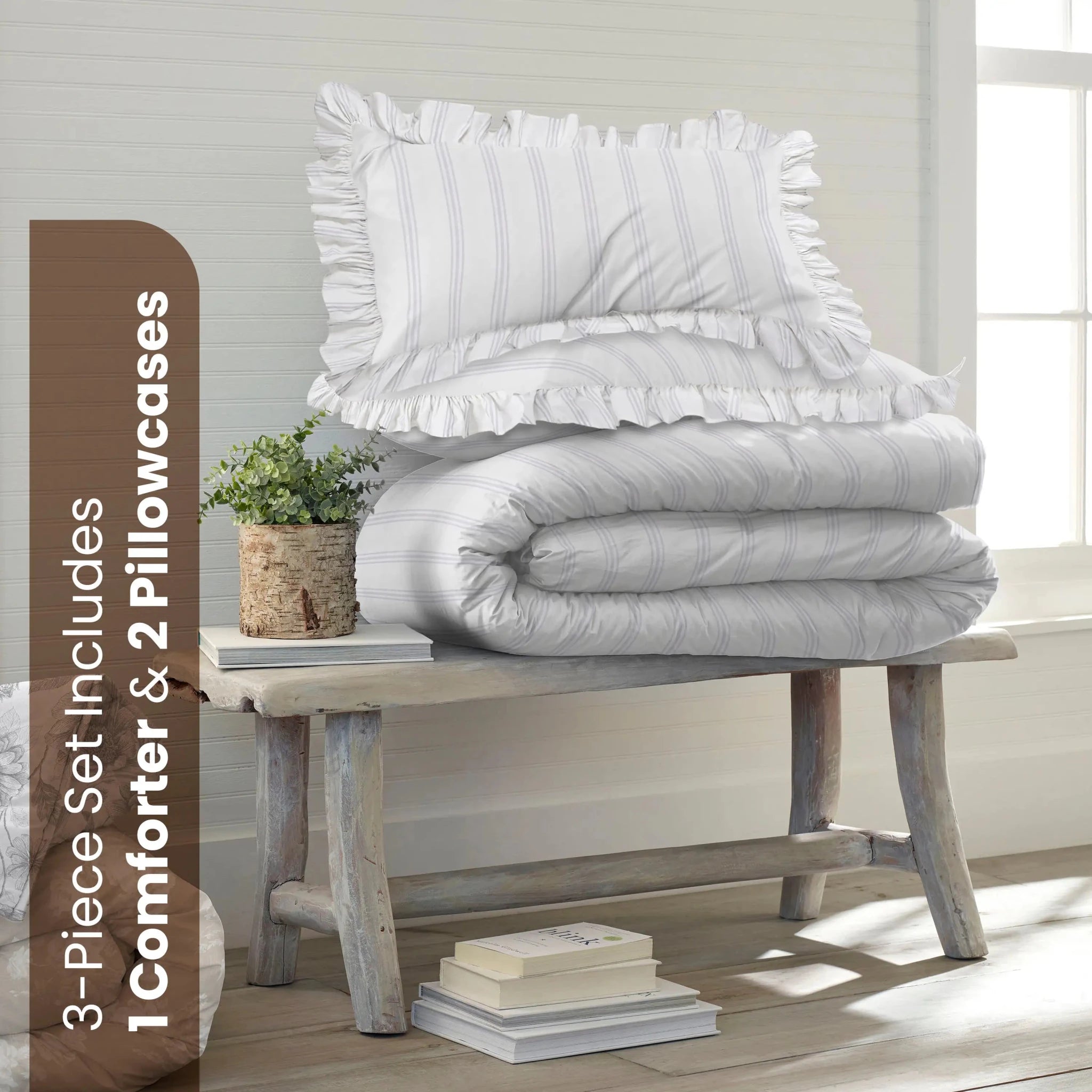 A striped comforter bedding set consisting of a comforter and two pillowcases, neatly stacked on a rustic wooden bench in a bright, sunlit room. A brown vertical banner on the left reads '3-Piece Set Includes 1 Comforter & 2 Pillowcases'.