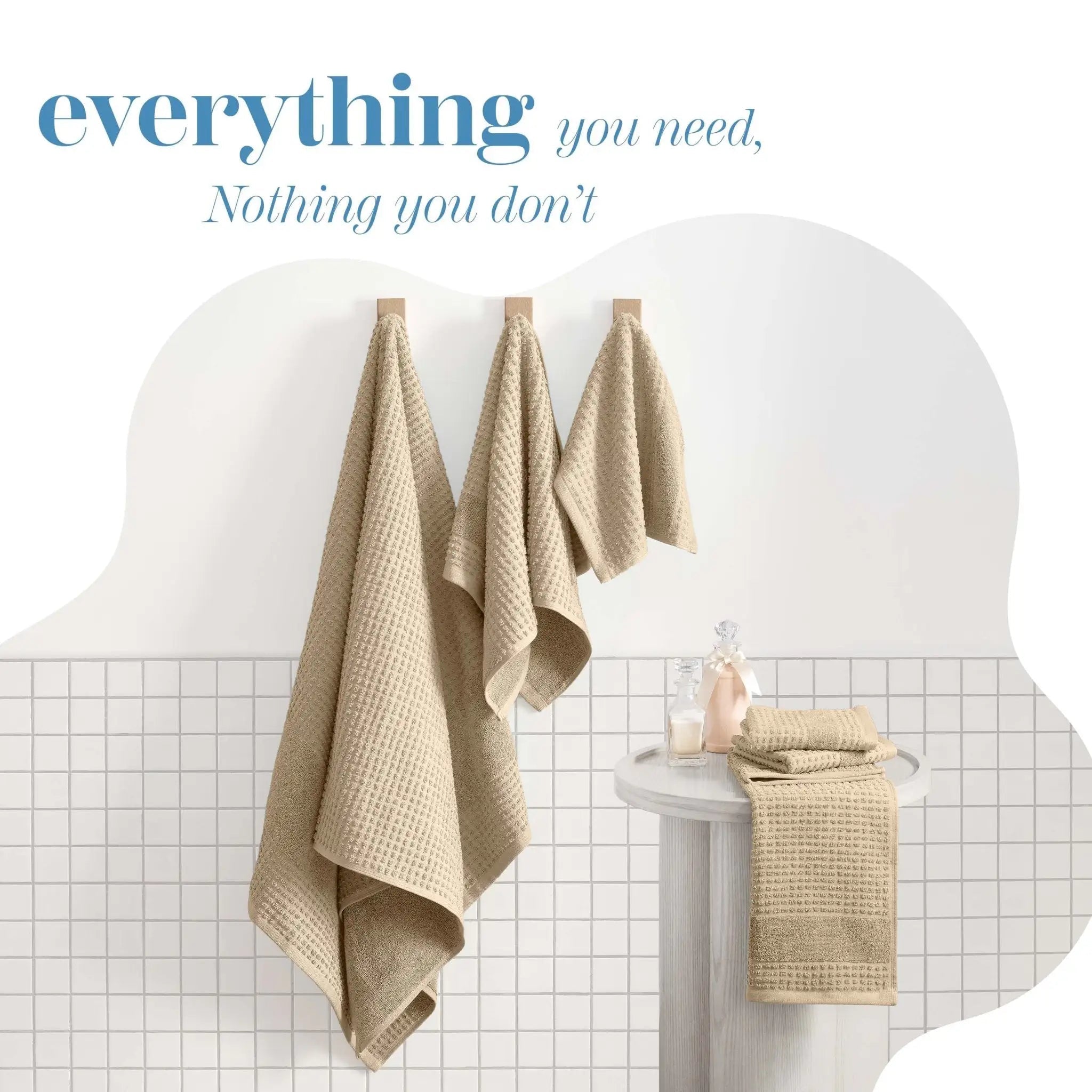 Sand towels hanging on a rack against a white tiled wall with text 'everything you need, Nothing you don't'.