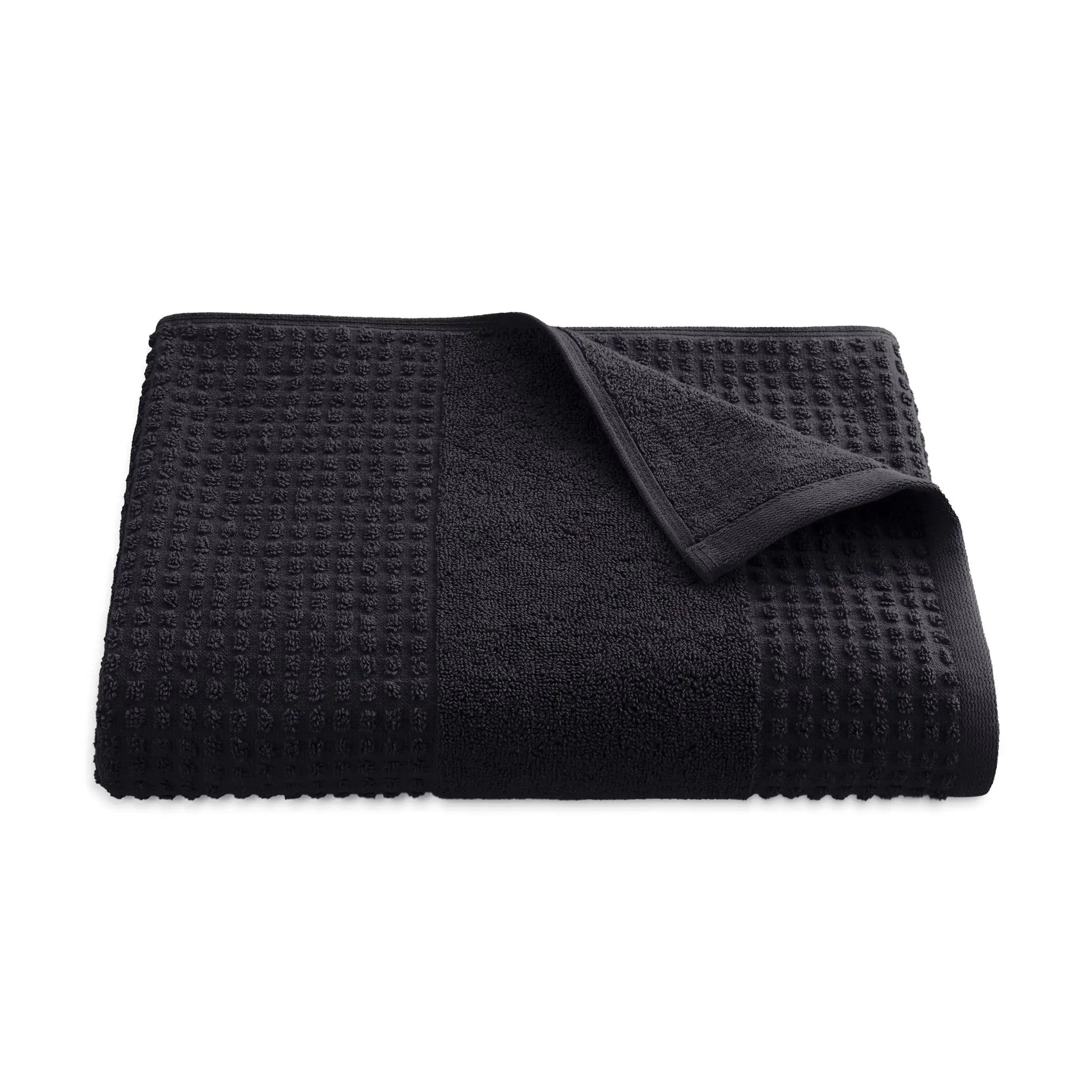 Folded black textured bath towel on a white background