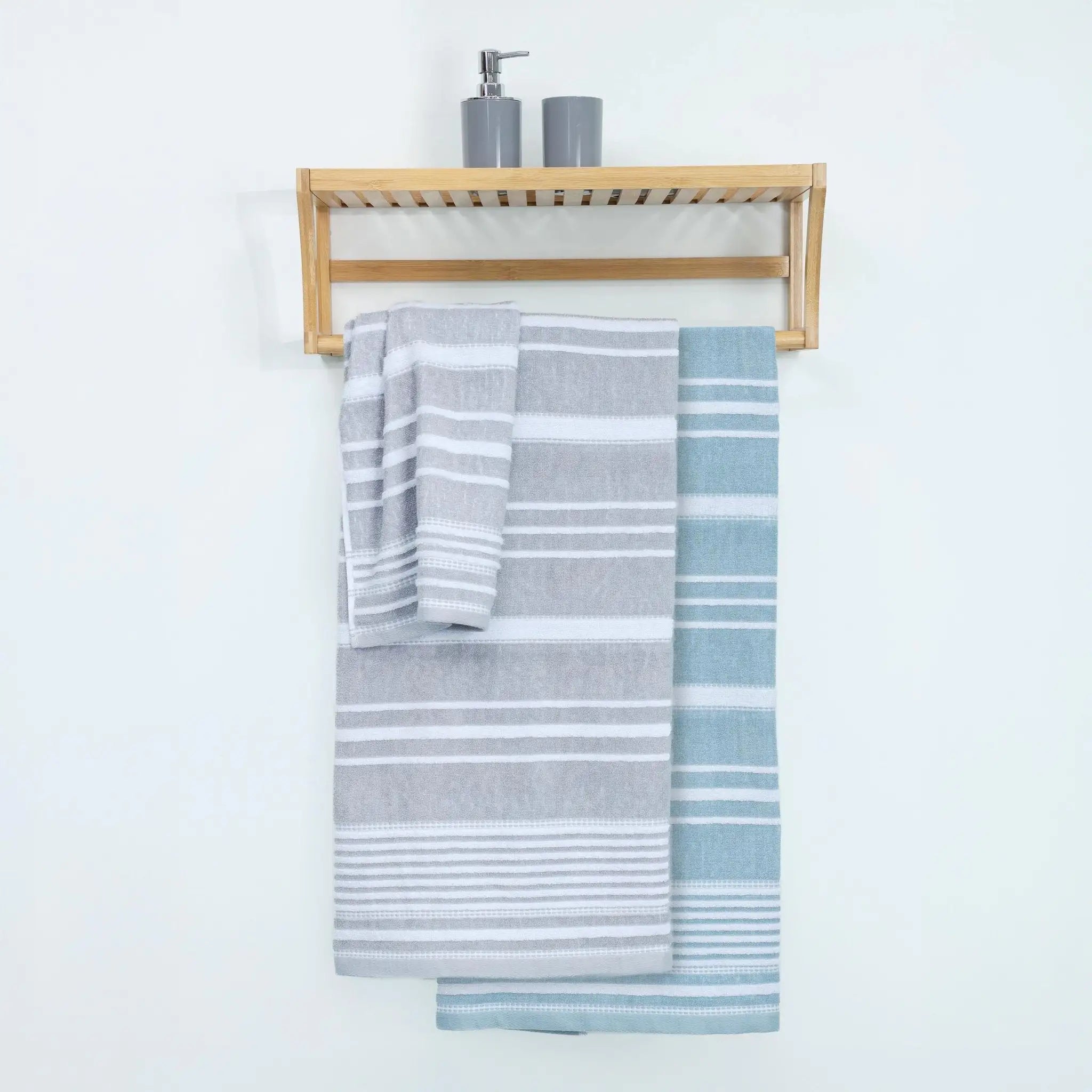 A light wood wall-mounted towel rack with two striped towels hanging below: one gray and one mineral.