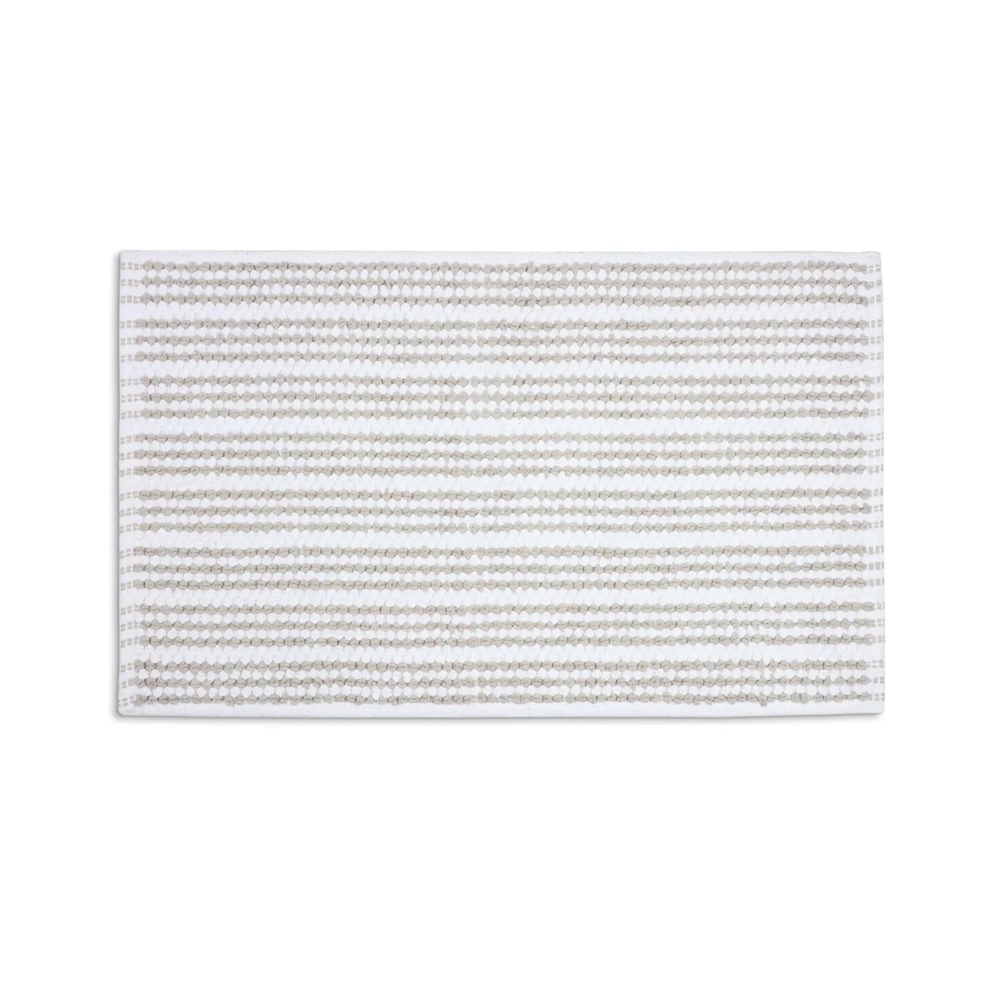 A rectangular sand color bath rug with horizontal stripes, shown flat against a solid white background.