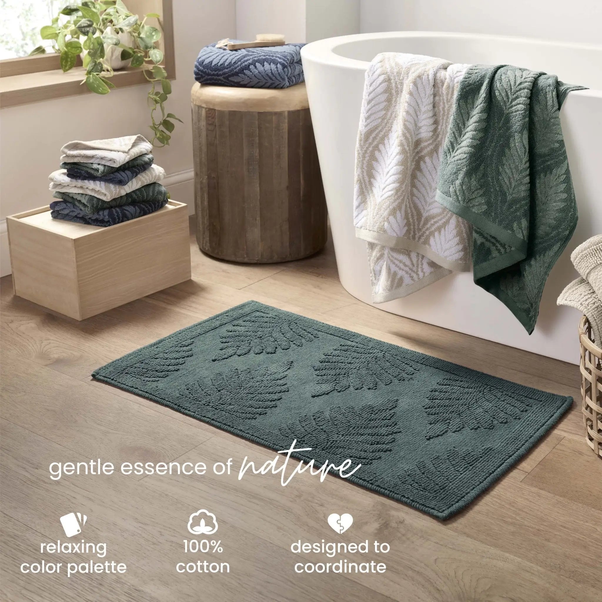 A jade bath rug with a raised leaf pattern is shown on a light wood floor in a bathroom setting next to a white freestanding tub. Text at the bottom reads 'gentle essence of nature' and includes feature callouts.