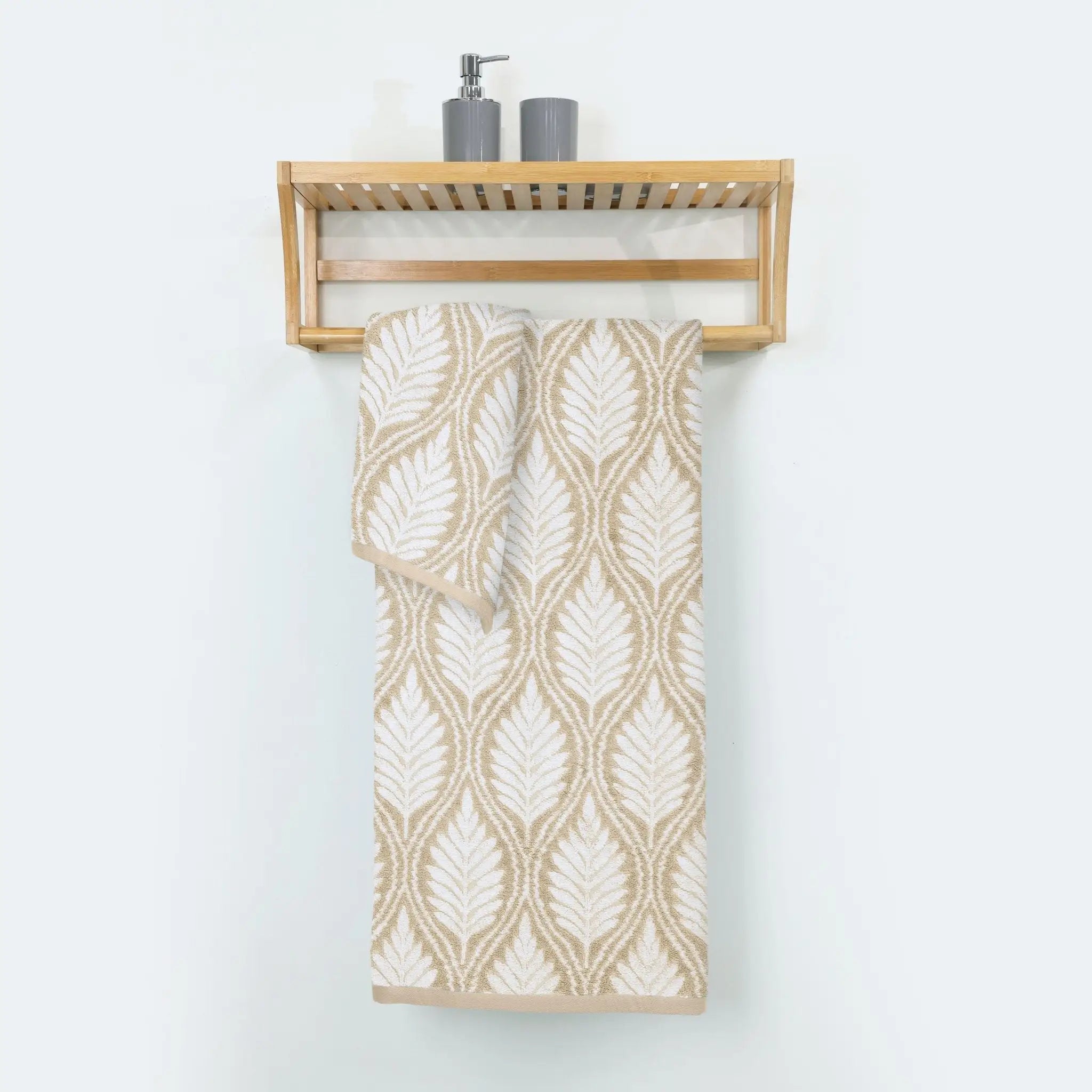 A sand patterned cotton bath towel hangs from a light wood wall-mounted shelf.