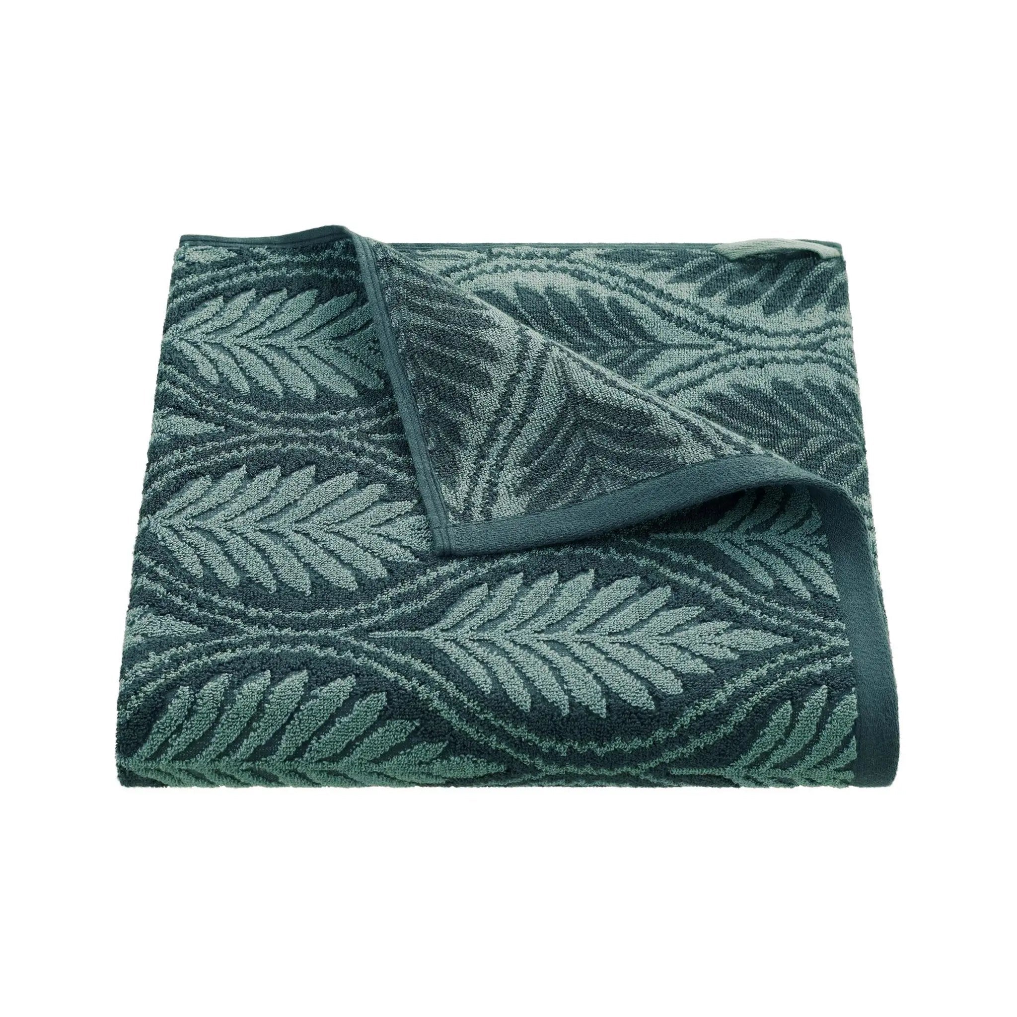 Folded jade bath towel with leaf pattern on a white background