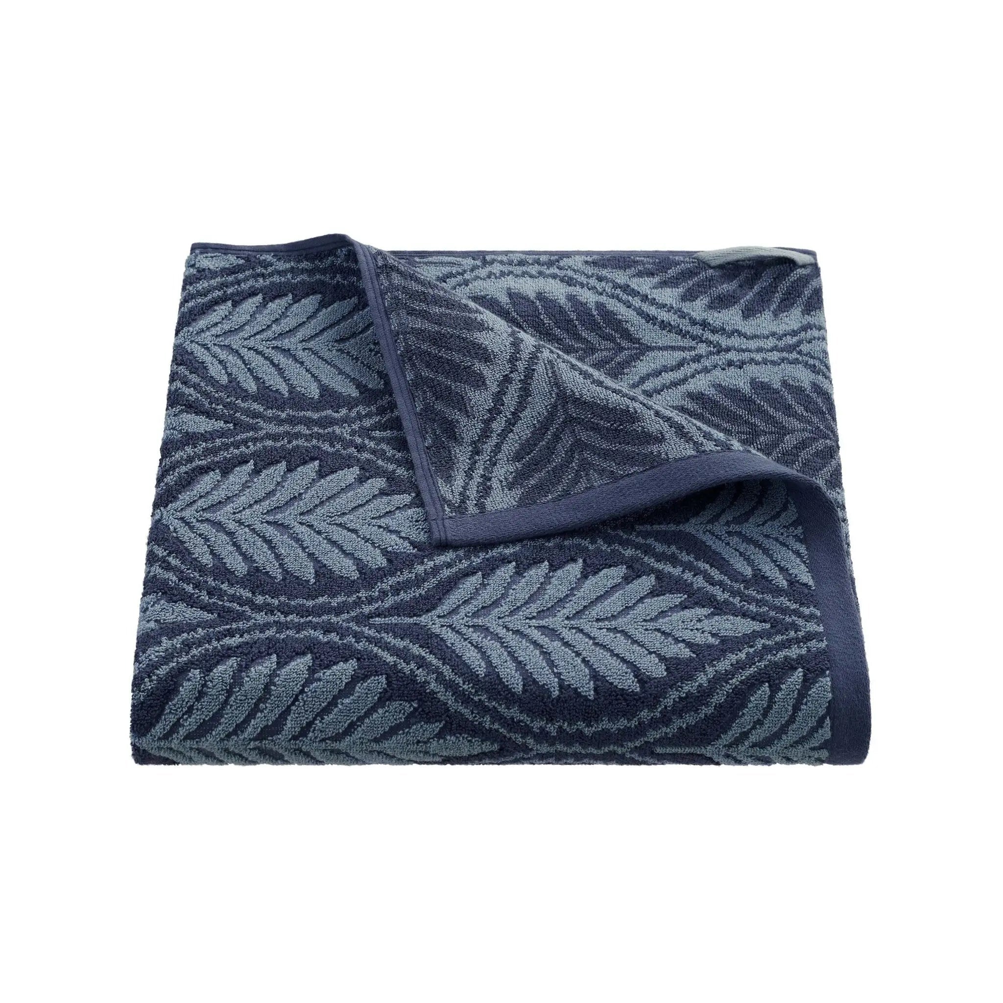 Folded navy patterned bath towel on a white background