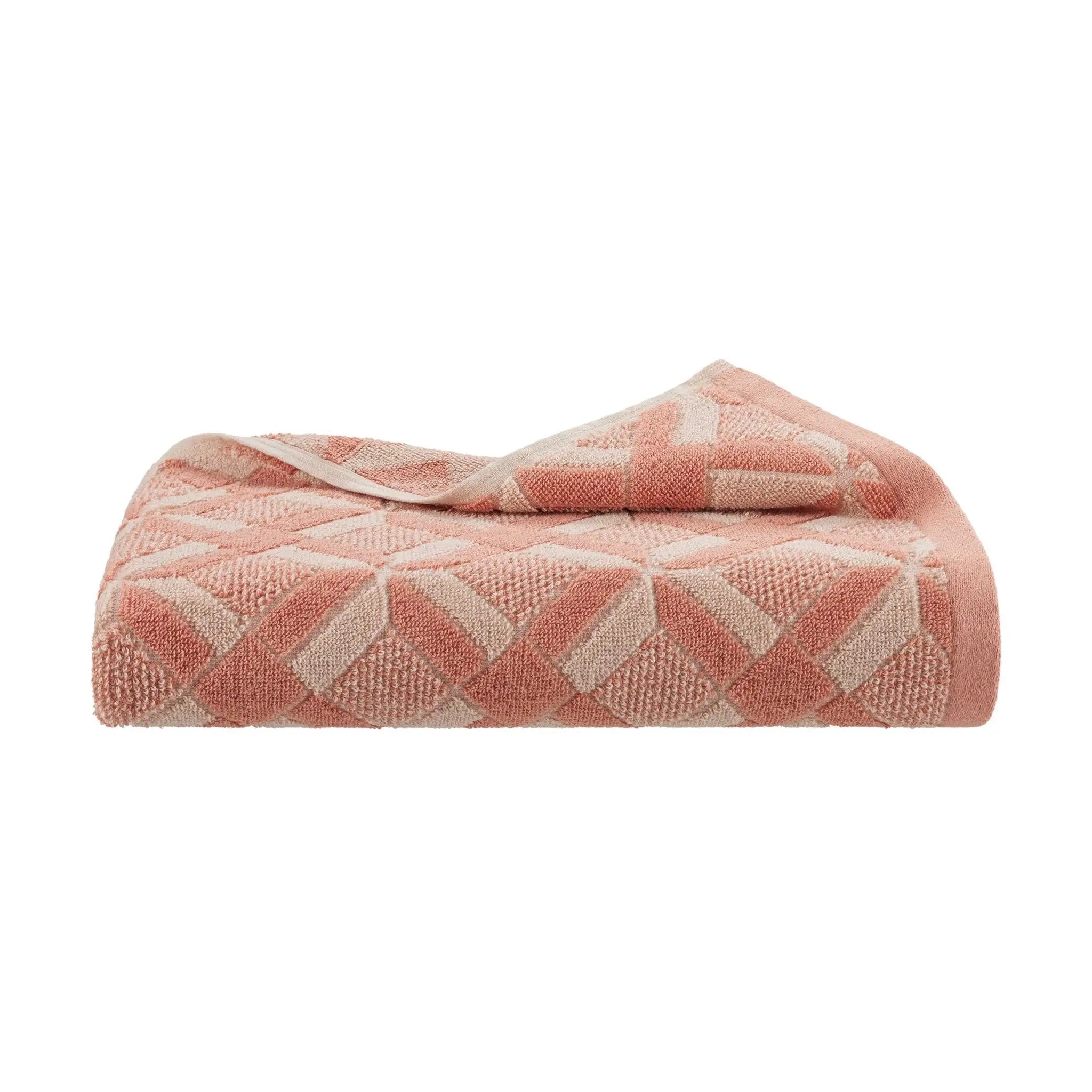 Folded clay colored patterned bath towel on a white background