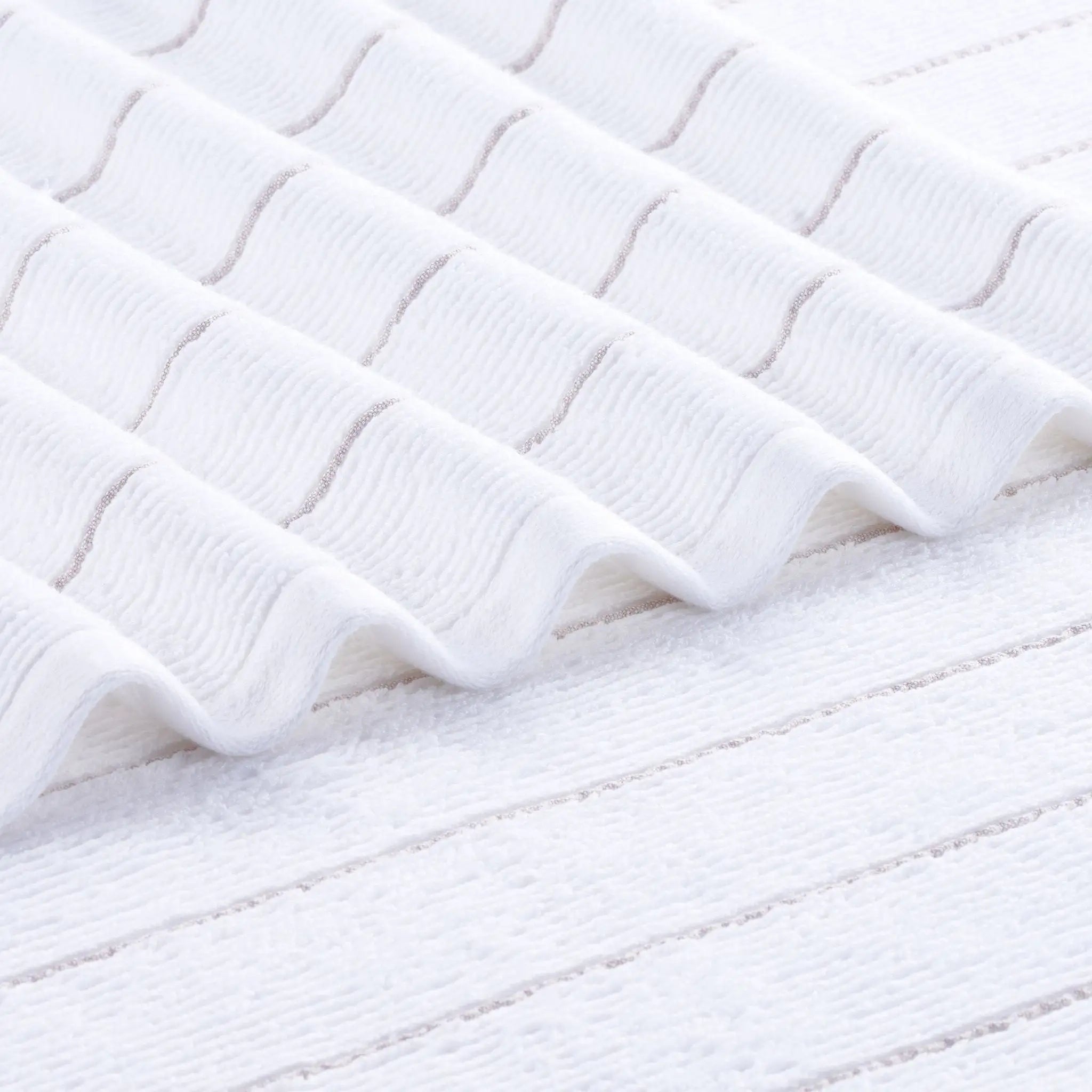 A close-up of a white textured fabric towel with a wavy, ribbed pattern and soft, plush loops.