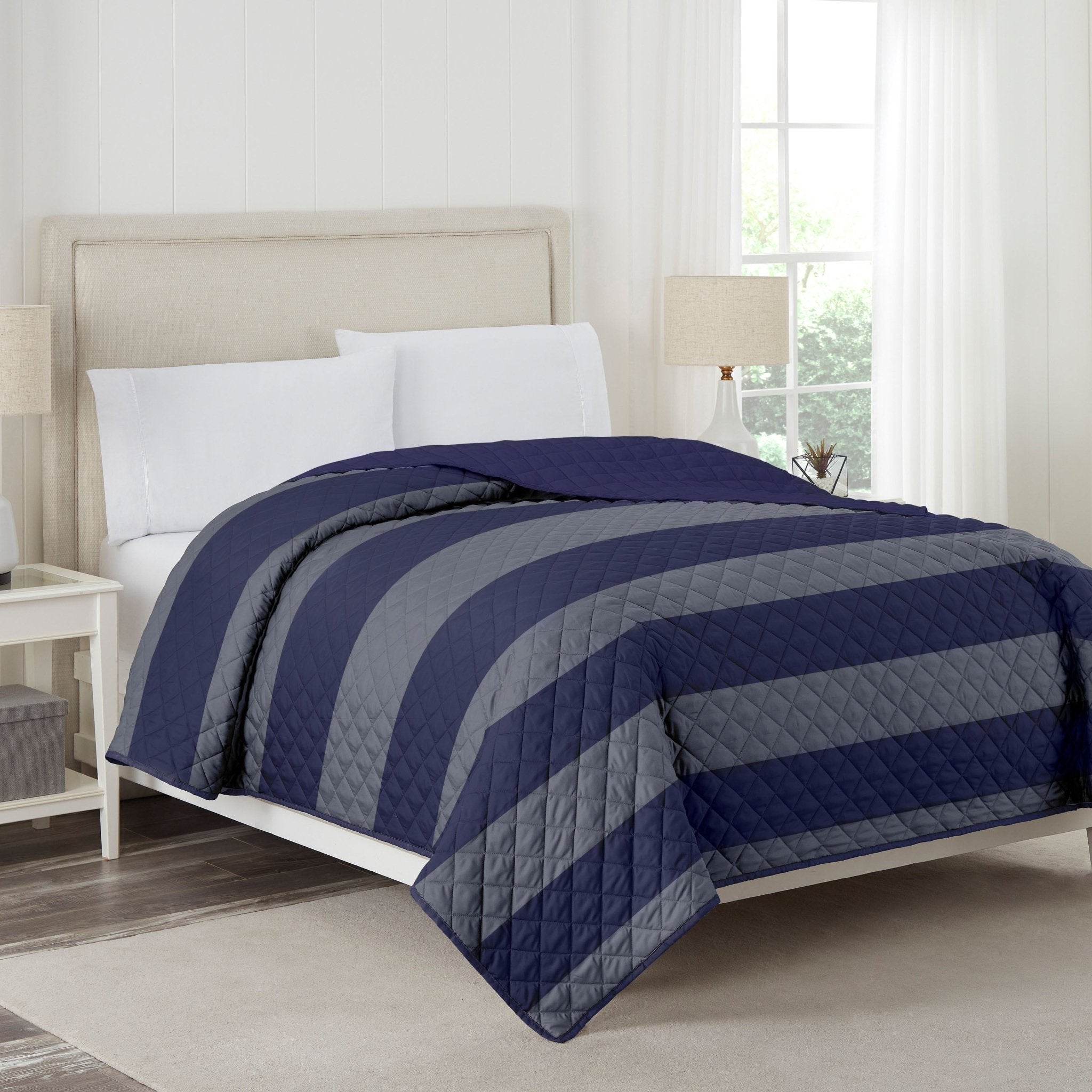 Bed with navy and gray striped coverlet in a bedroom setting