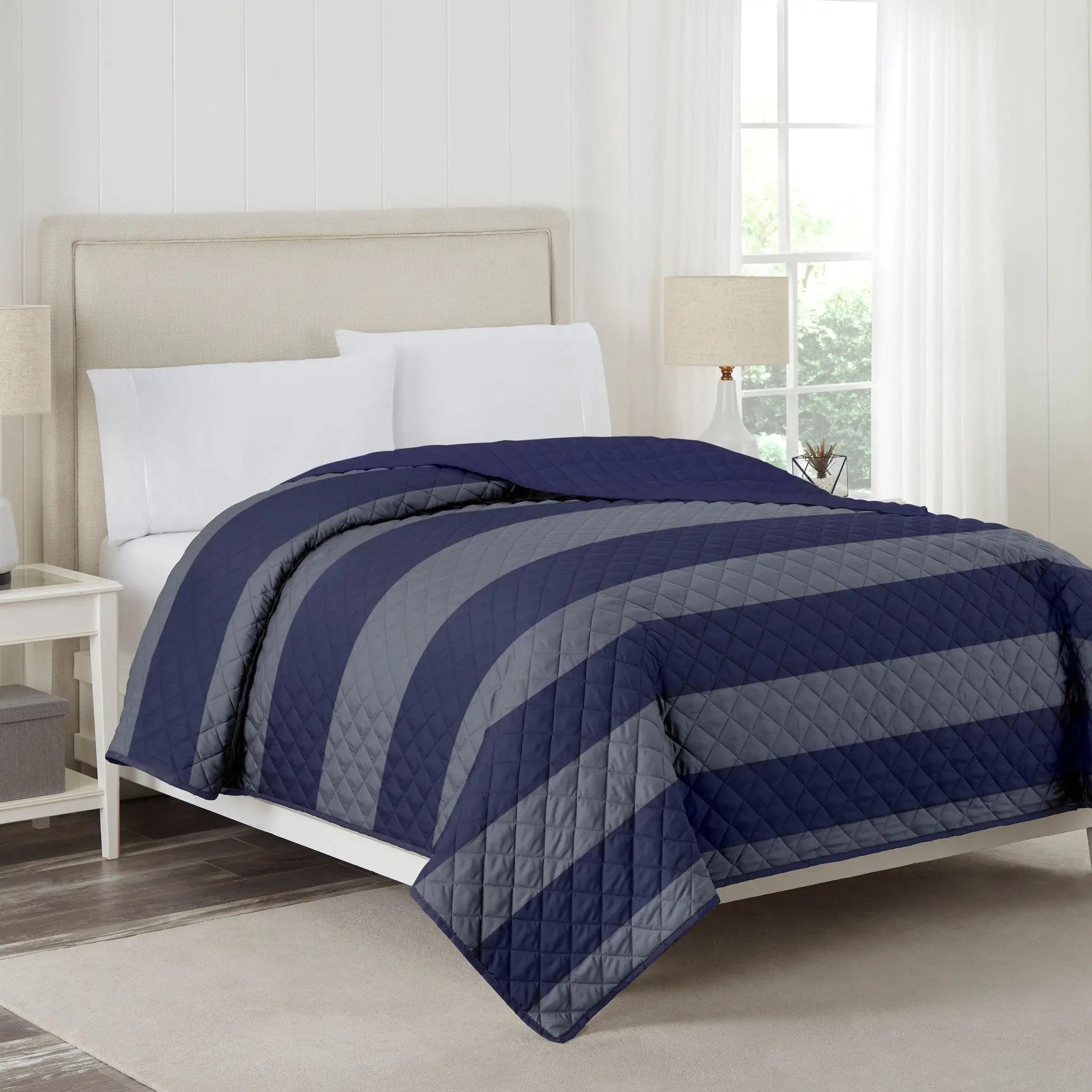 Bed with navy and gray striped coverlet in a bedroom setting