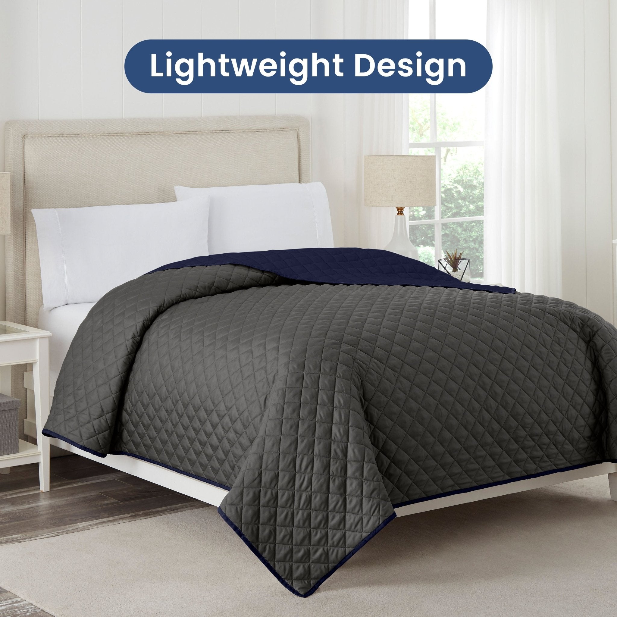 Graphite coverlet with navy reversible on a bed in a bedroom setting, labeled 'Lightweight Design'.