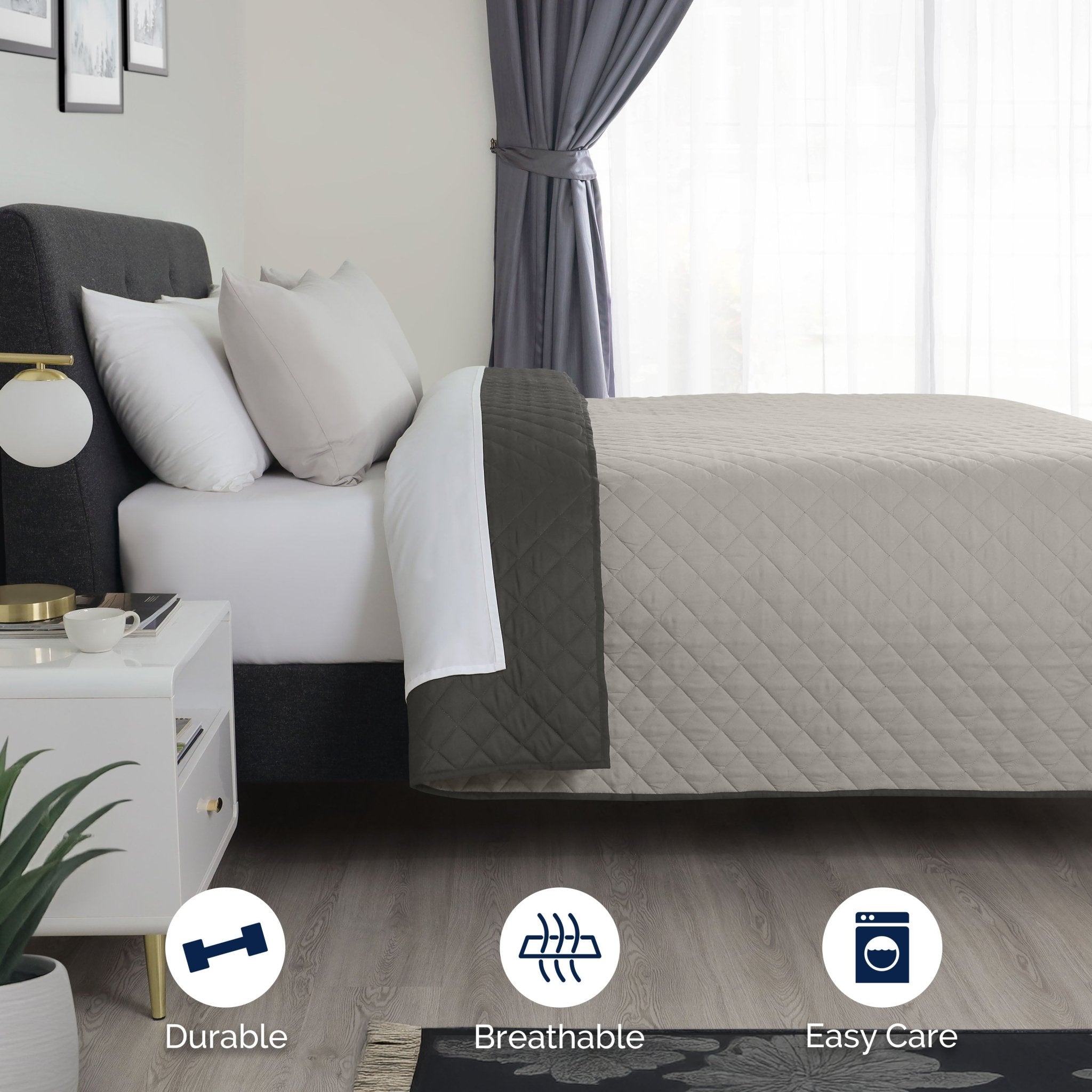 Bed with light gray/graphite coverlet in a bedroom setting.