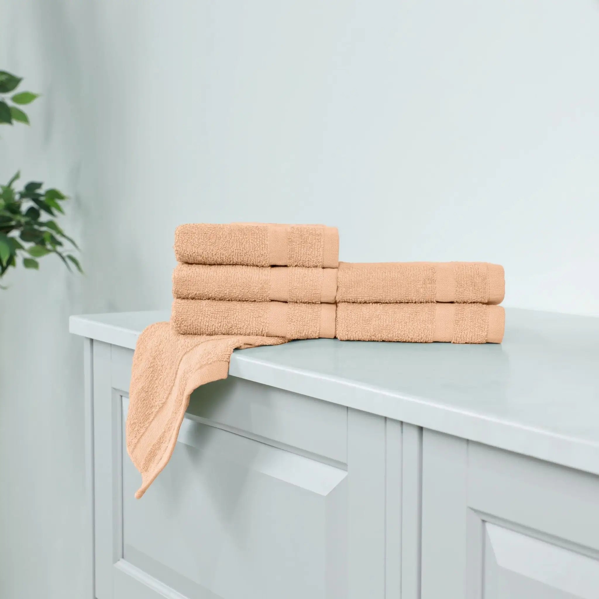 Stack of peach-colored washcloths on a white cabinet.