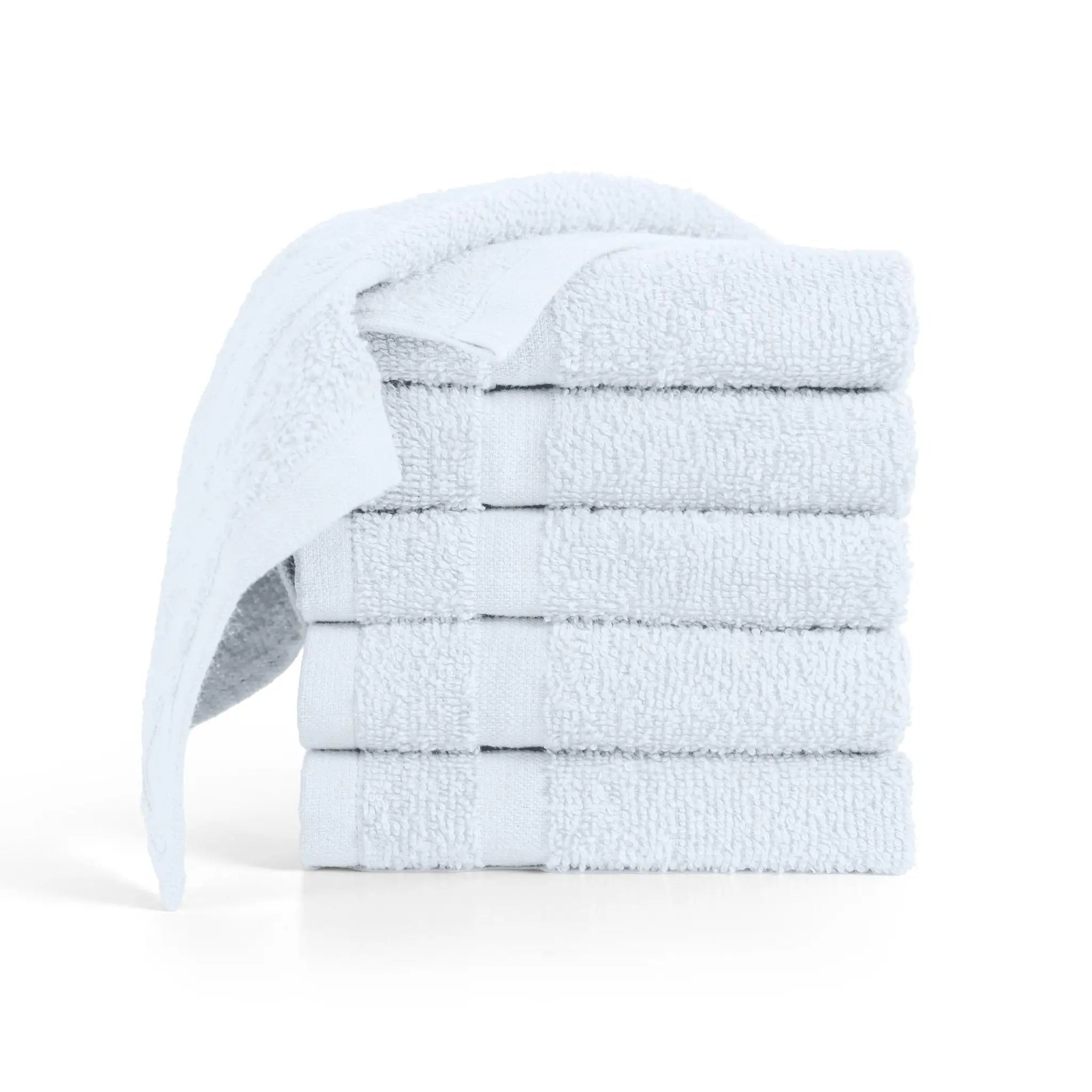 A stack of five folded white washcloths with one washcloth draped over the side.