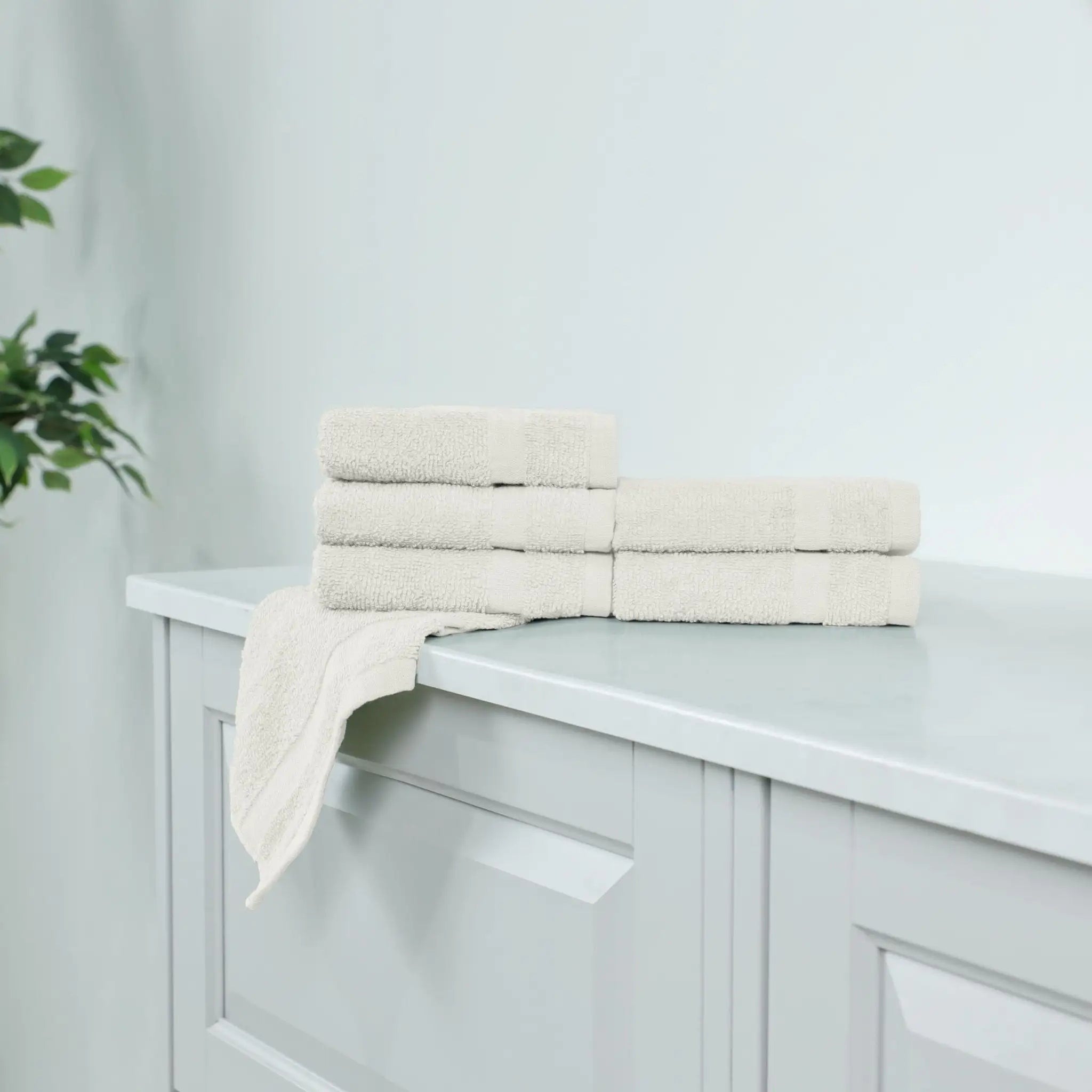 Ivory washcloth stacked on a white cabinet.