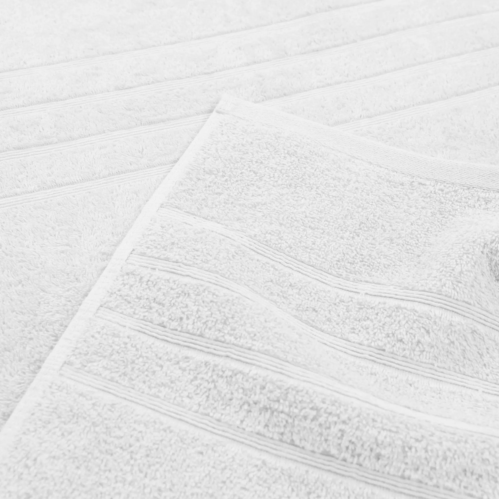 A close-up of a white bath towel with textured terry cloth and horizontal ribbed stripes.