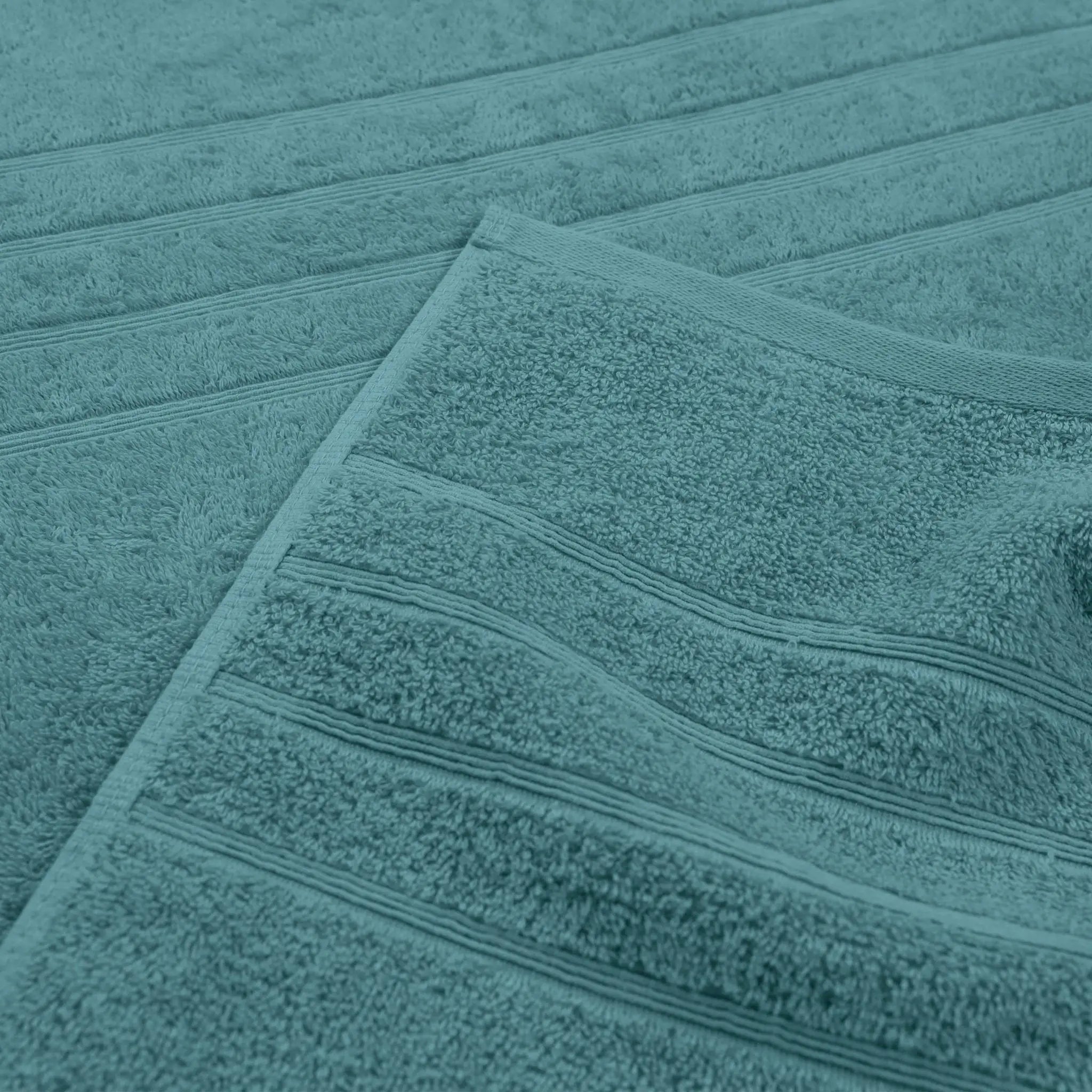 A close-up of a larkspur teal bath towel with horizontal ribbed stripes, folded over to show its soft texture.