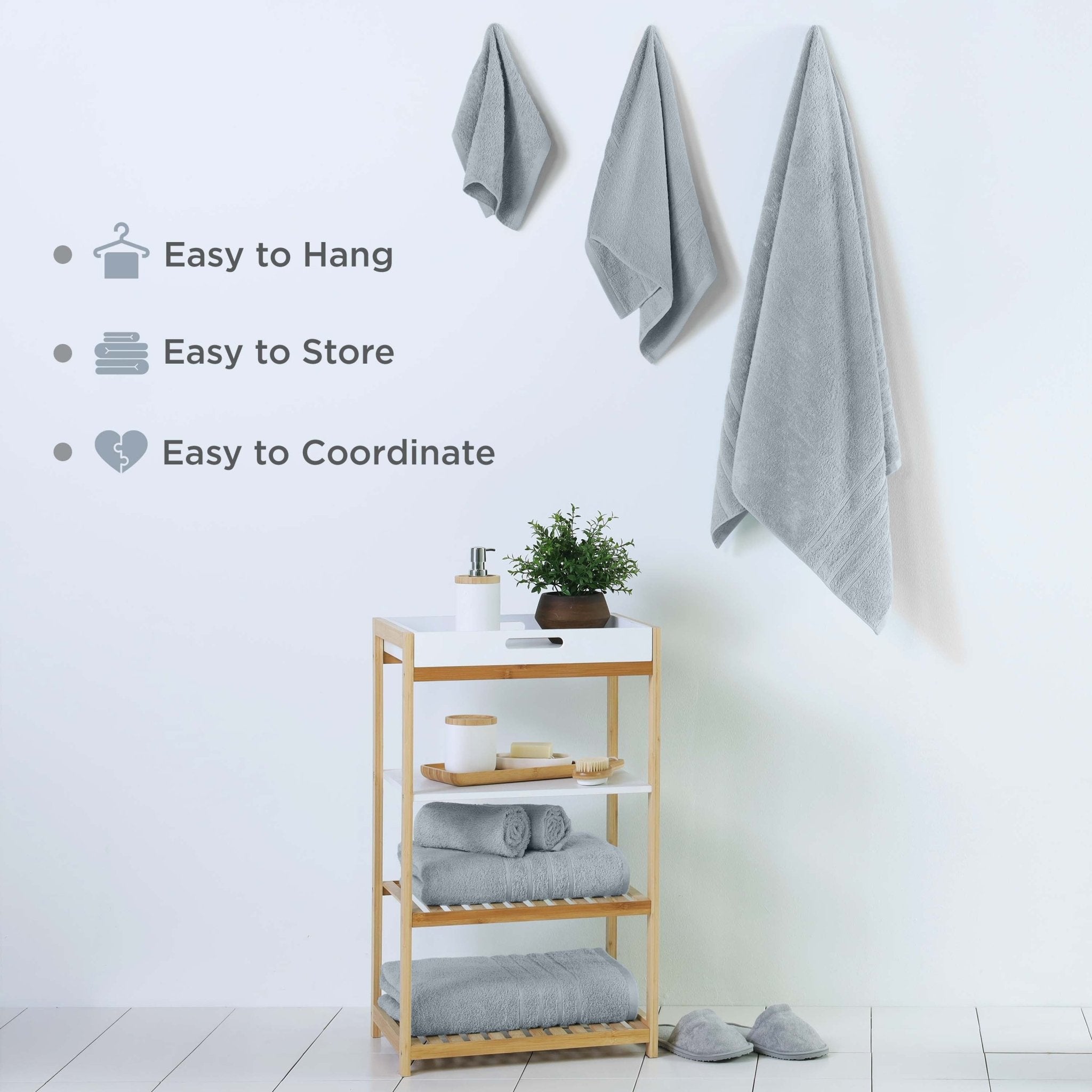 Towel rack with spa blue towels and a plant on a white wall.