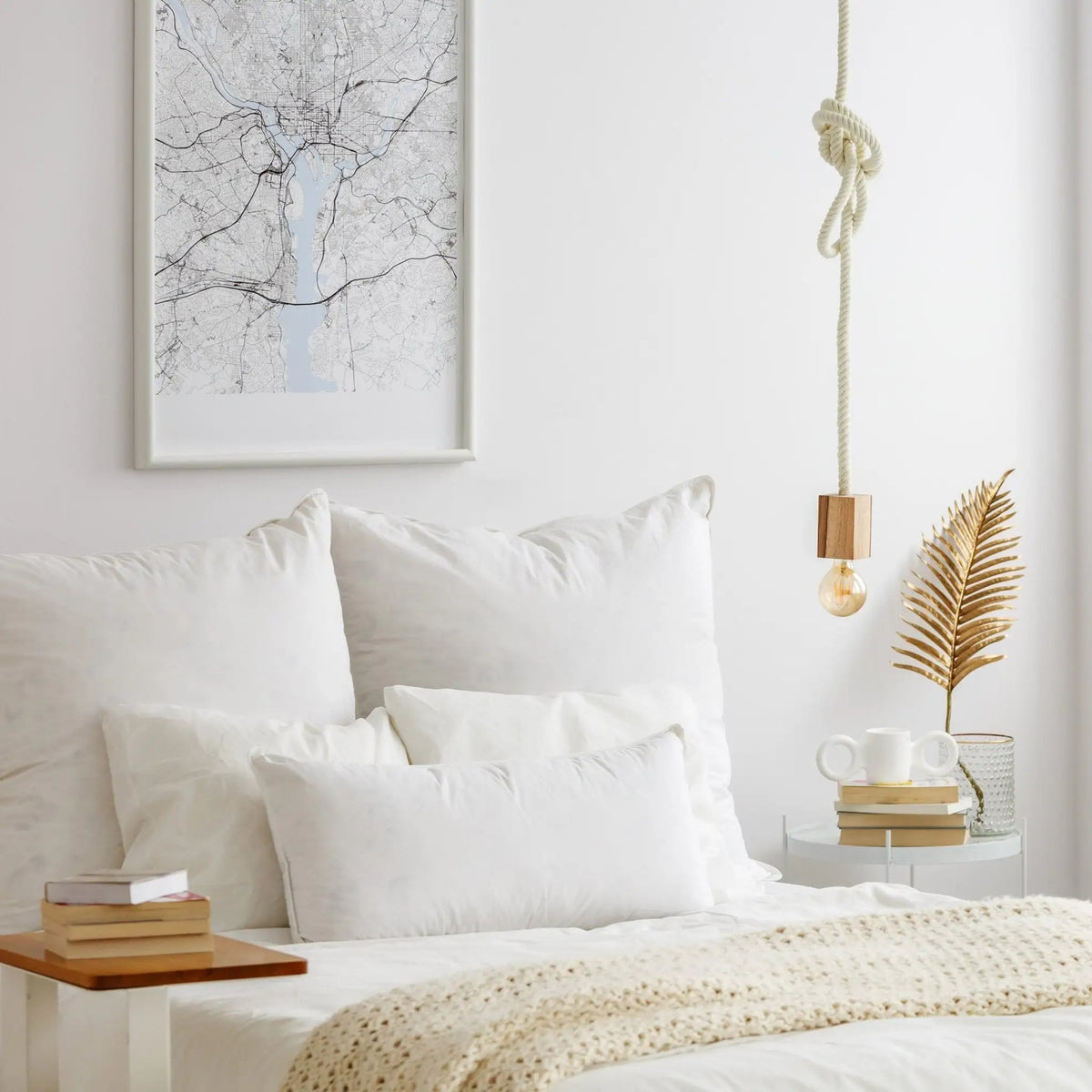 Neatly made bed with white bedding and a framed map on the wall.