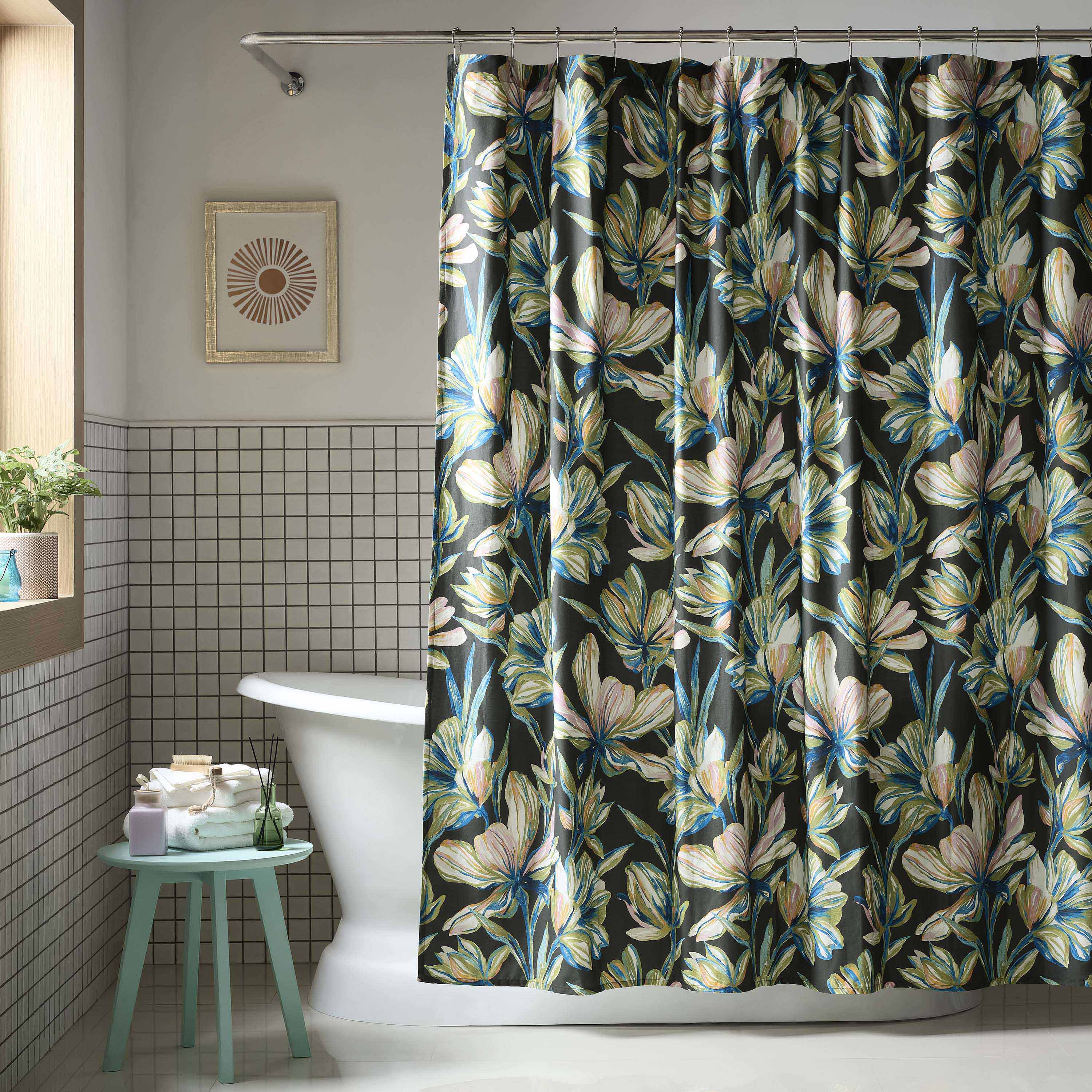 Shower curtain with a floral design in shades of green, blue, and white against a dark background, hanging in a bathroom.