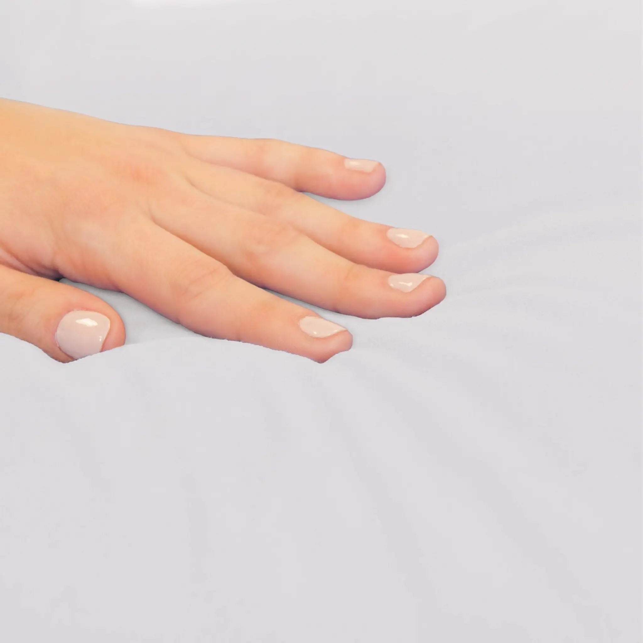 A close-up of a hand resting on a plain light gray surface.