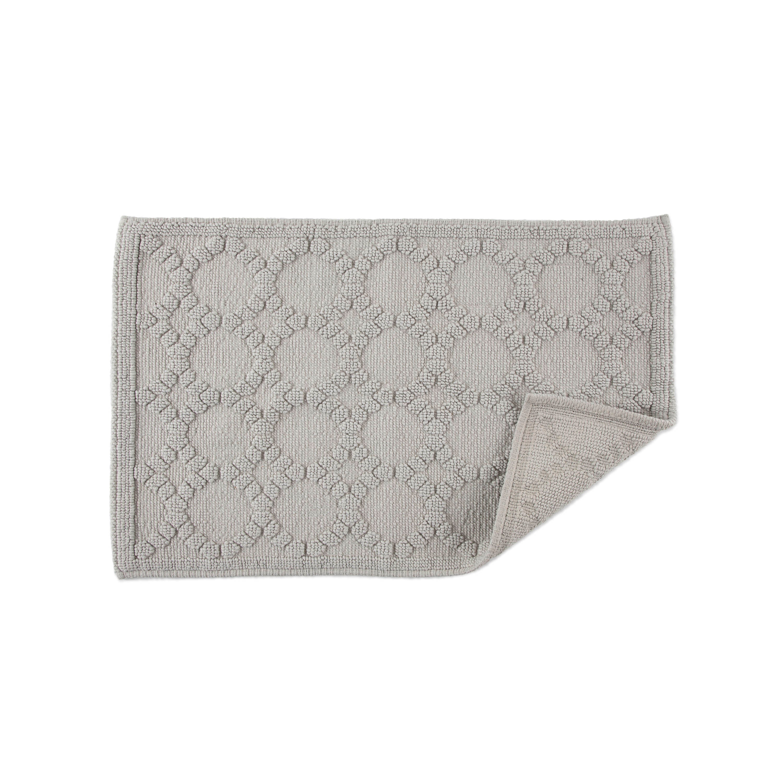 Gray bath rug with a textured circular pattern and a folded corner revealing the backing.
